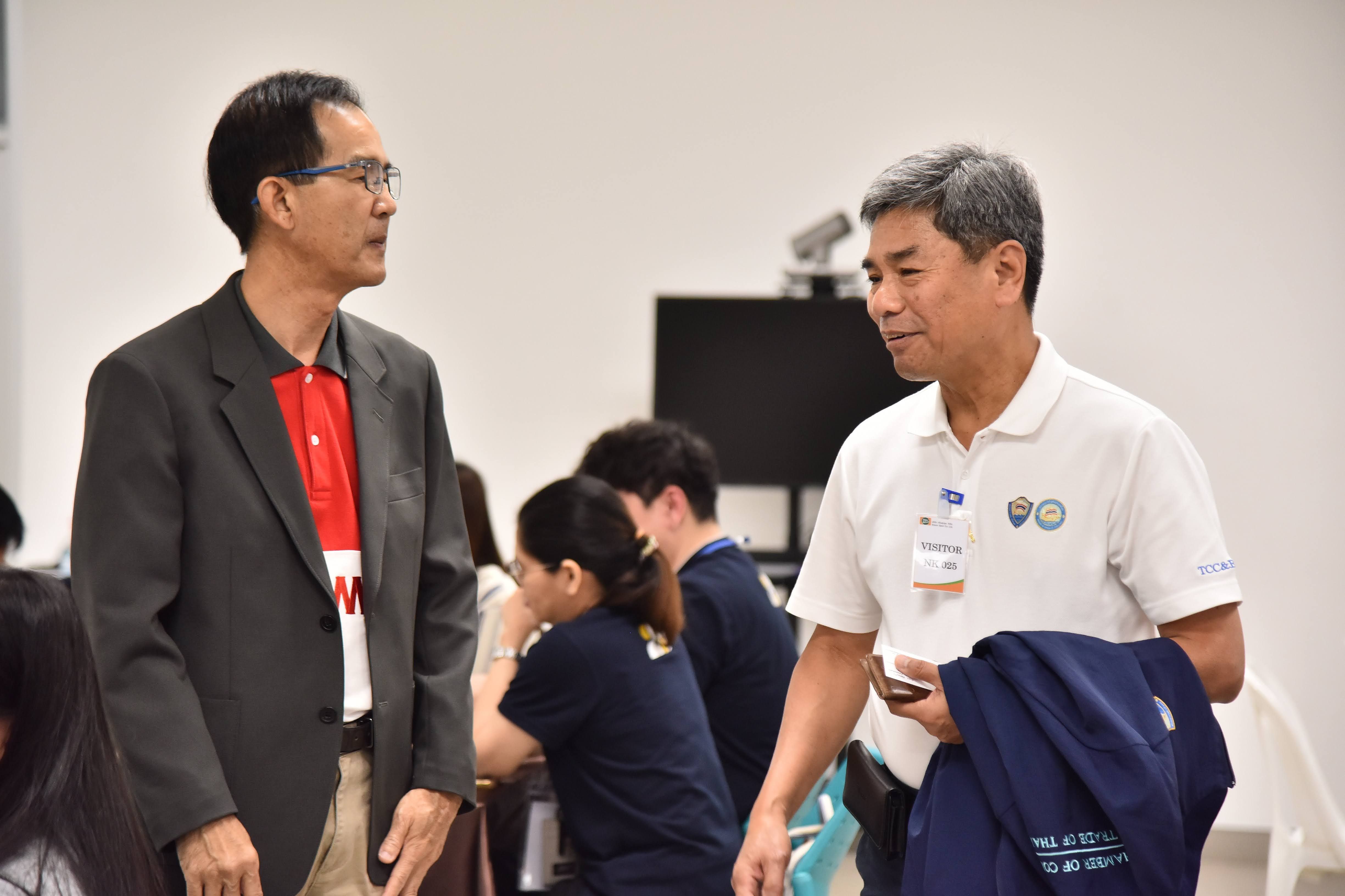 Two professional men in a room are engaged in a discussion.