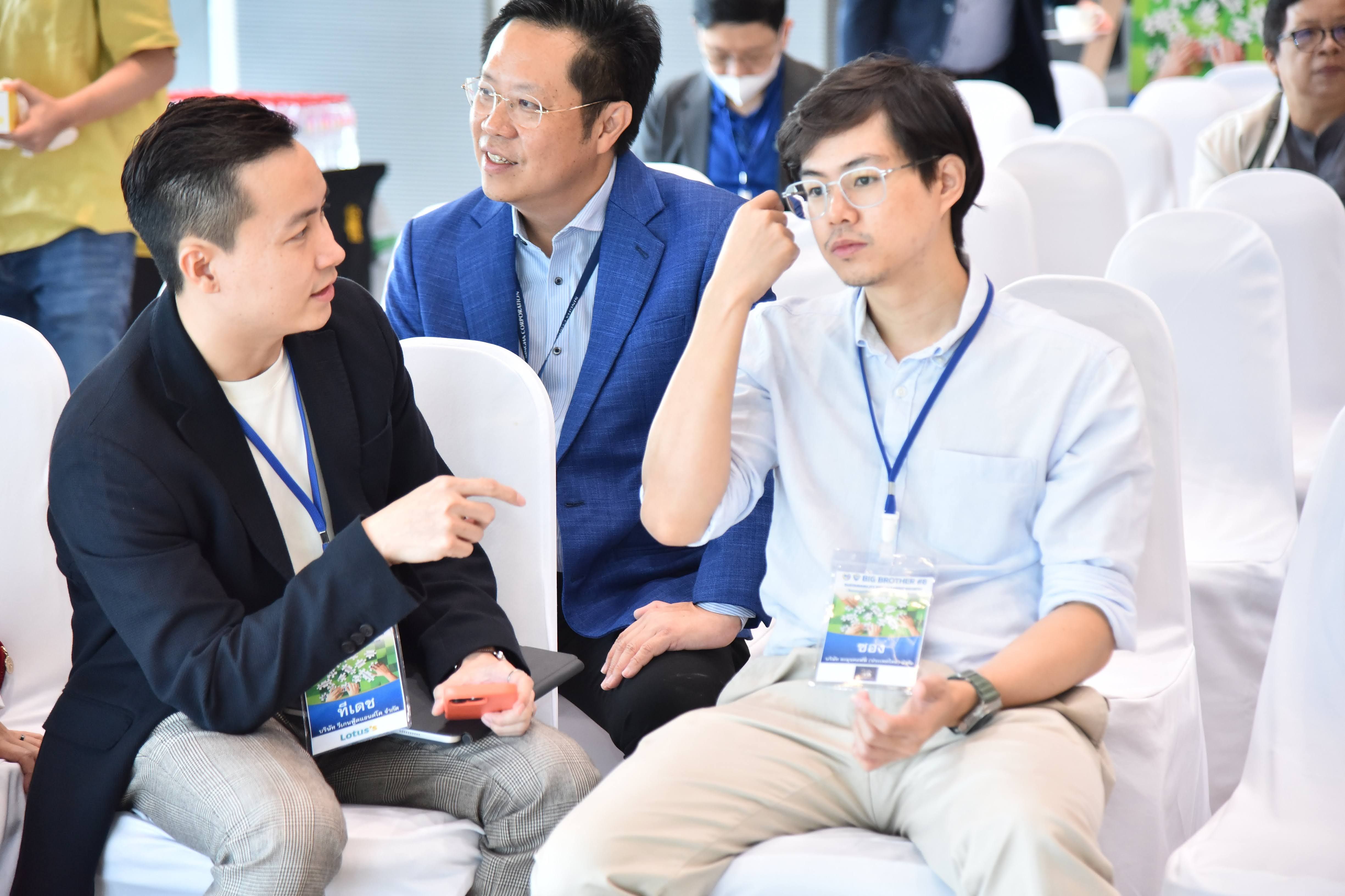 Two men discuss at a professional event, one pointing while the other listens attentively.