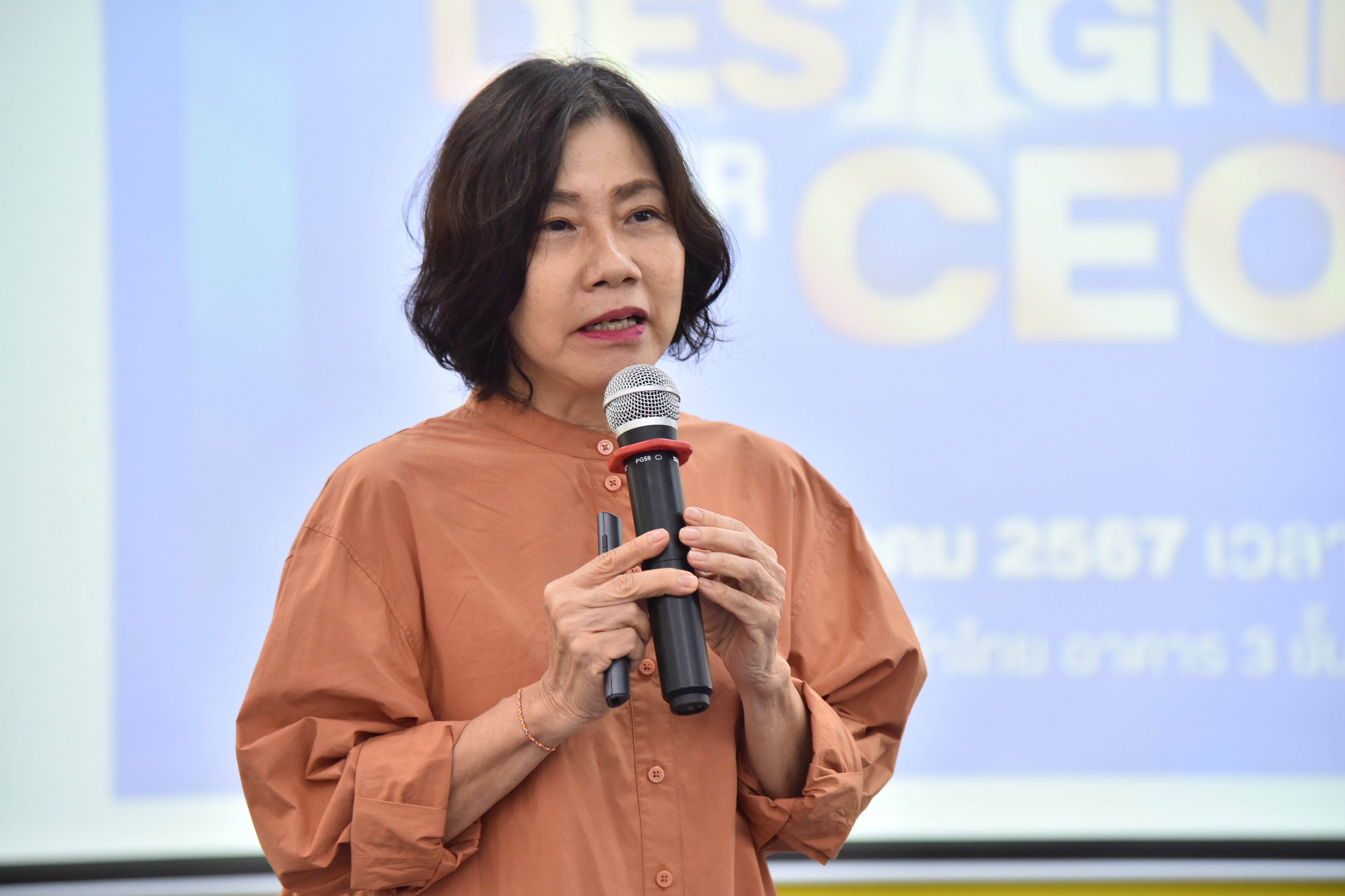 Woman with short dark hair speaking into a microphone at a professional event.