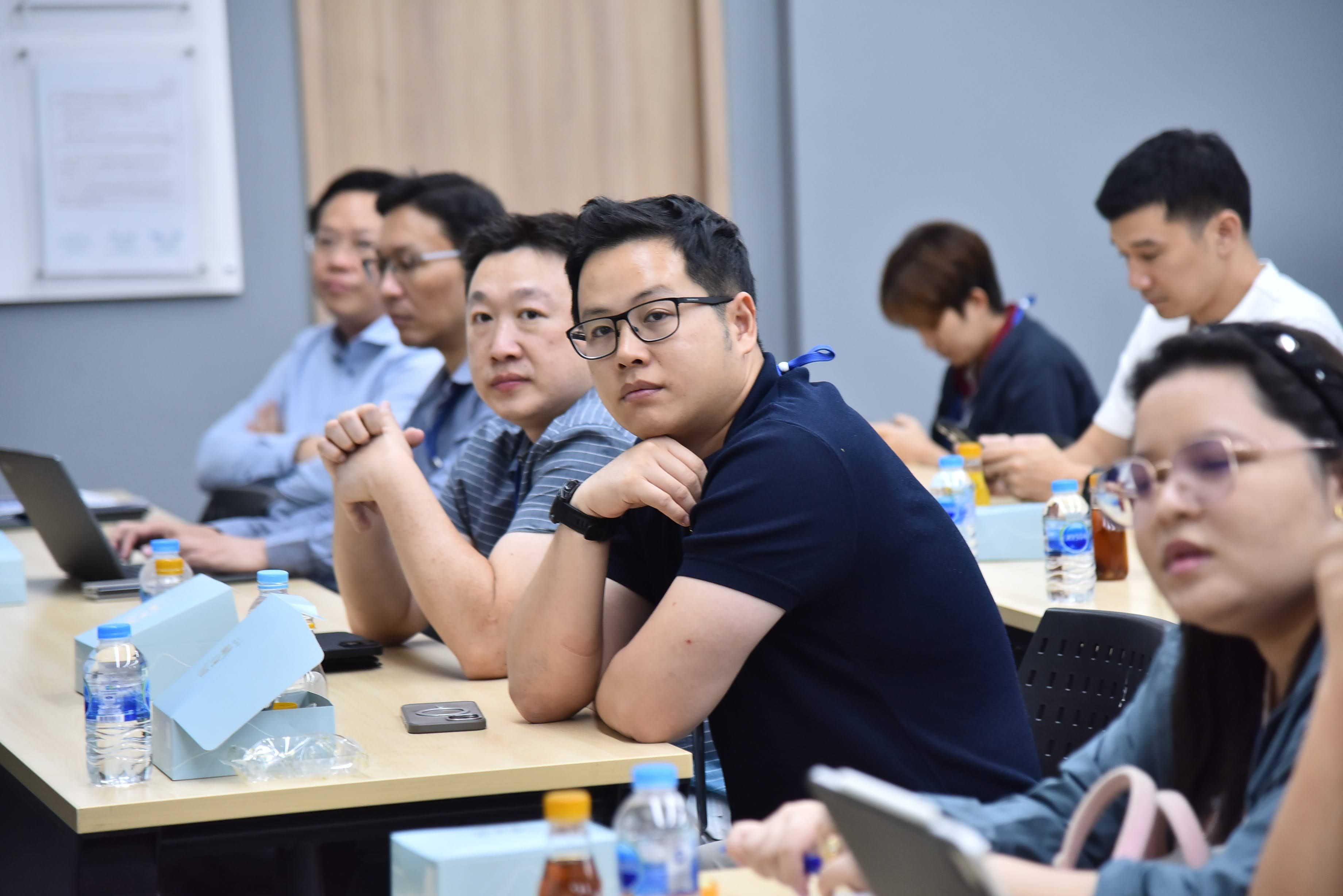 Attendees, including a man in glasses, focus during a professional meeting or seminar.