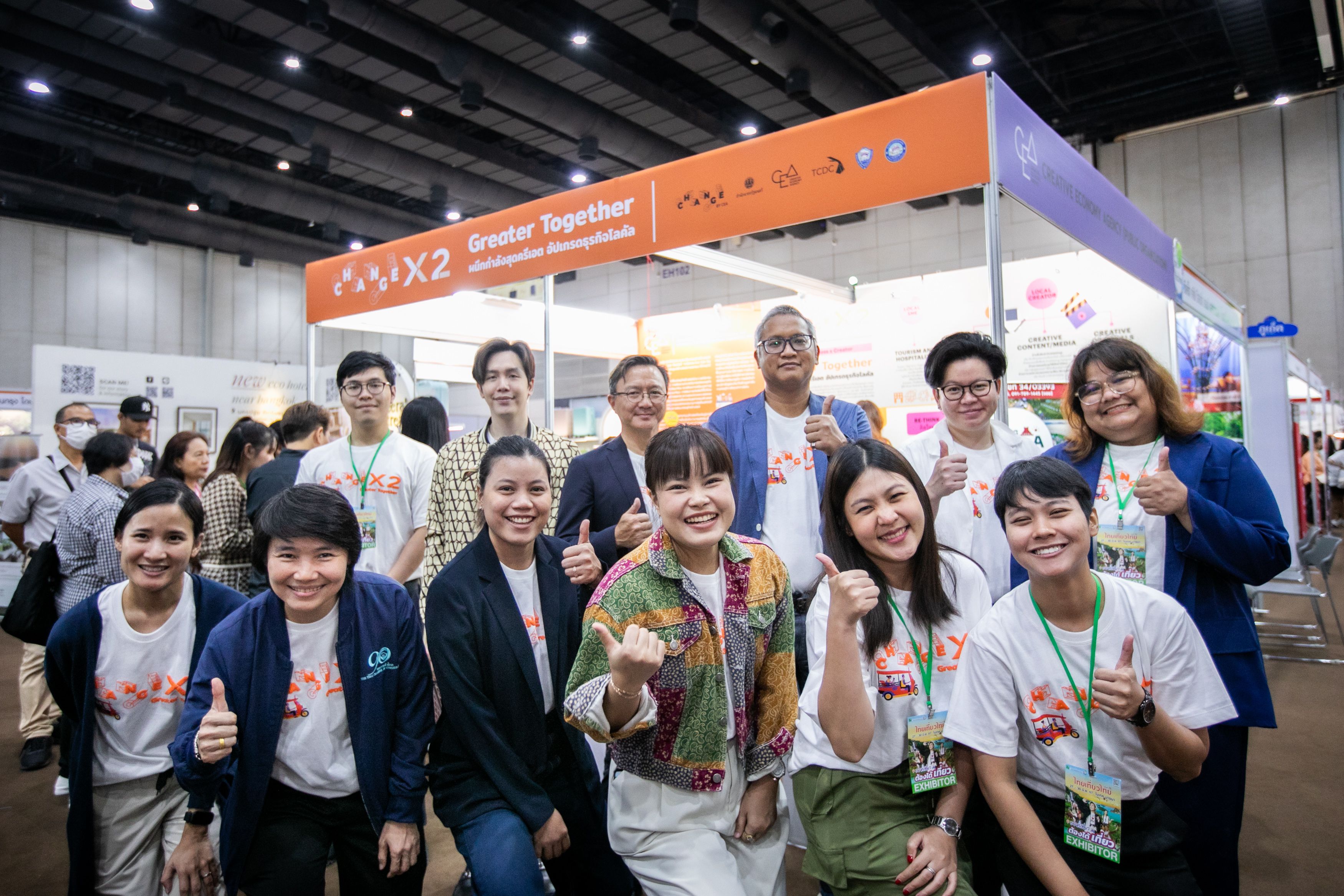 Diverse group smiling, giving thumbs-up in front of a 'Culture Together' booth at an event.