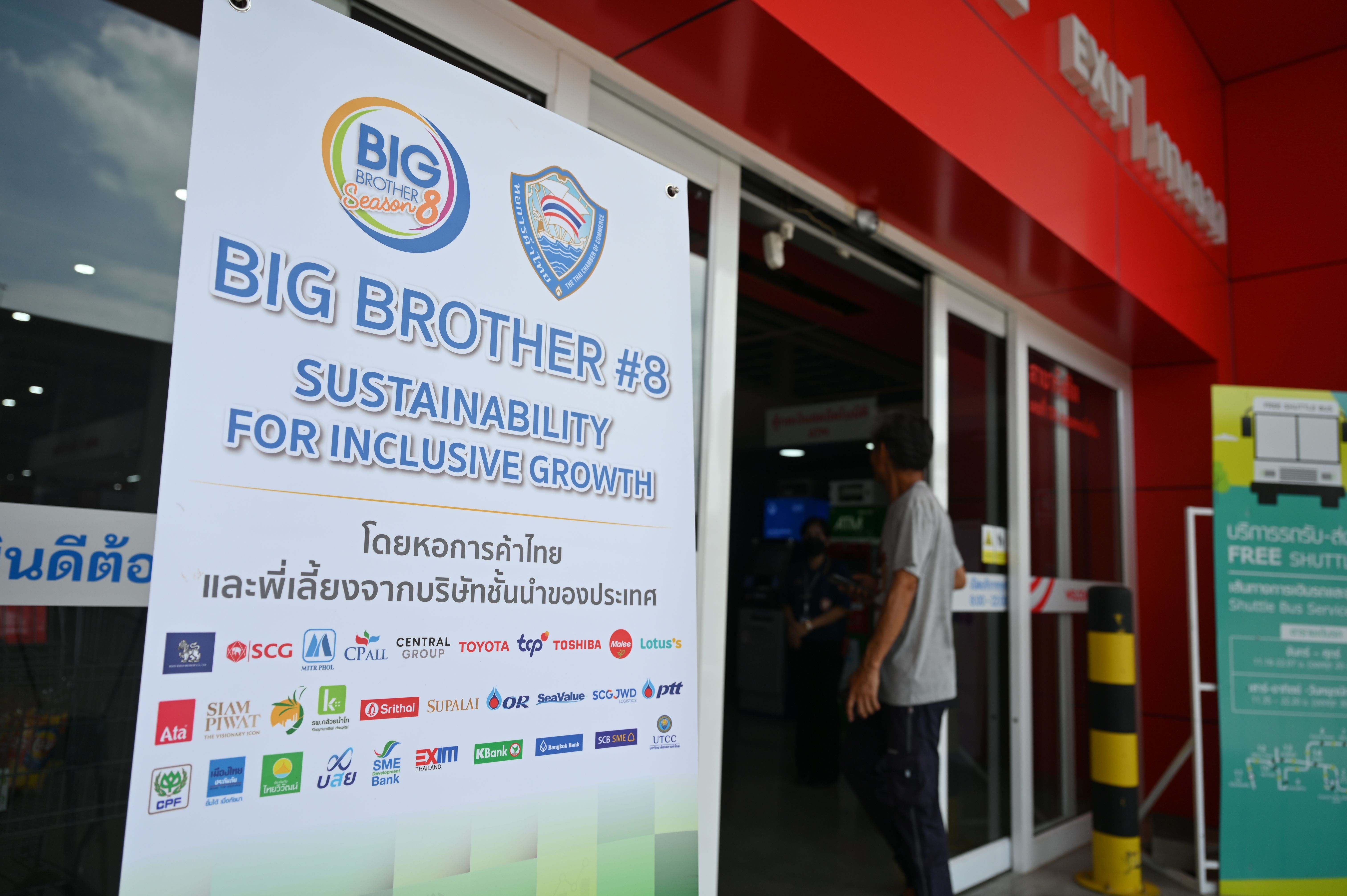 White sign promoting 'BIG BROTHER #8: SUSTAINABILITY FOR INCLUSIVE GROWTH' with company logos.