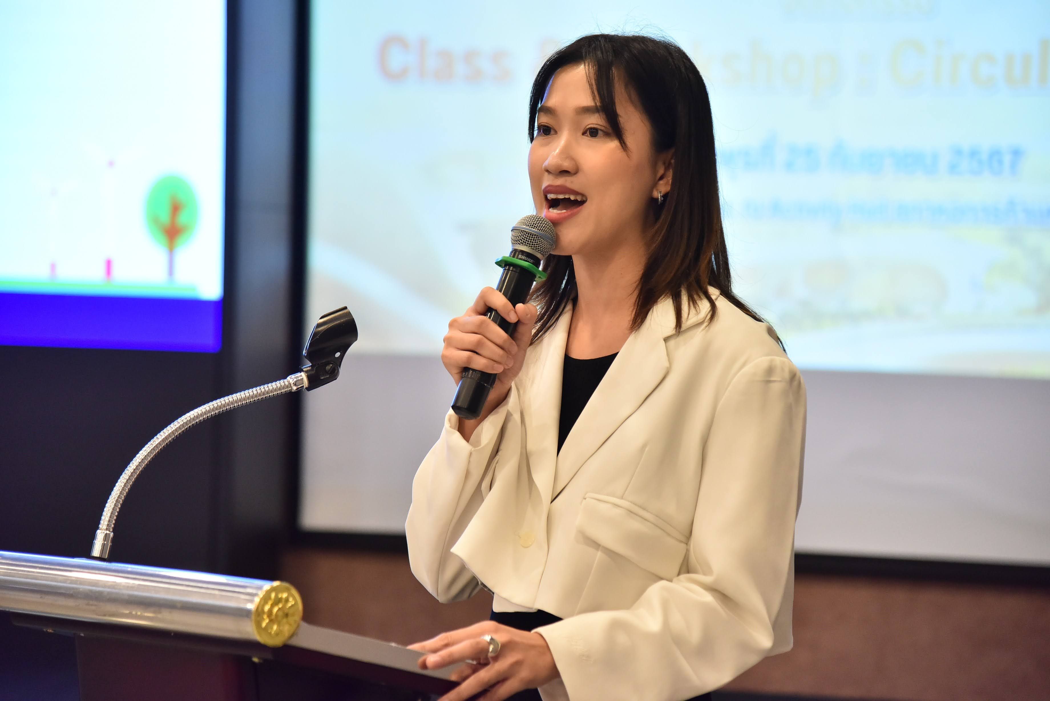 A woman with dark hair speaks into a microphone during a presentation event.