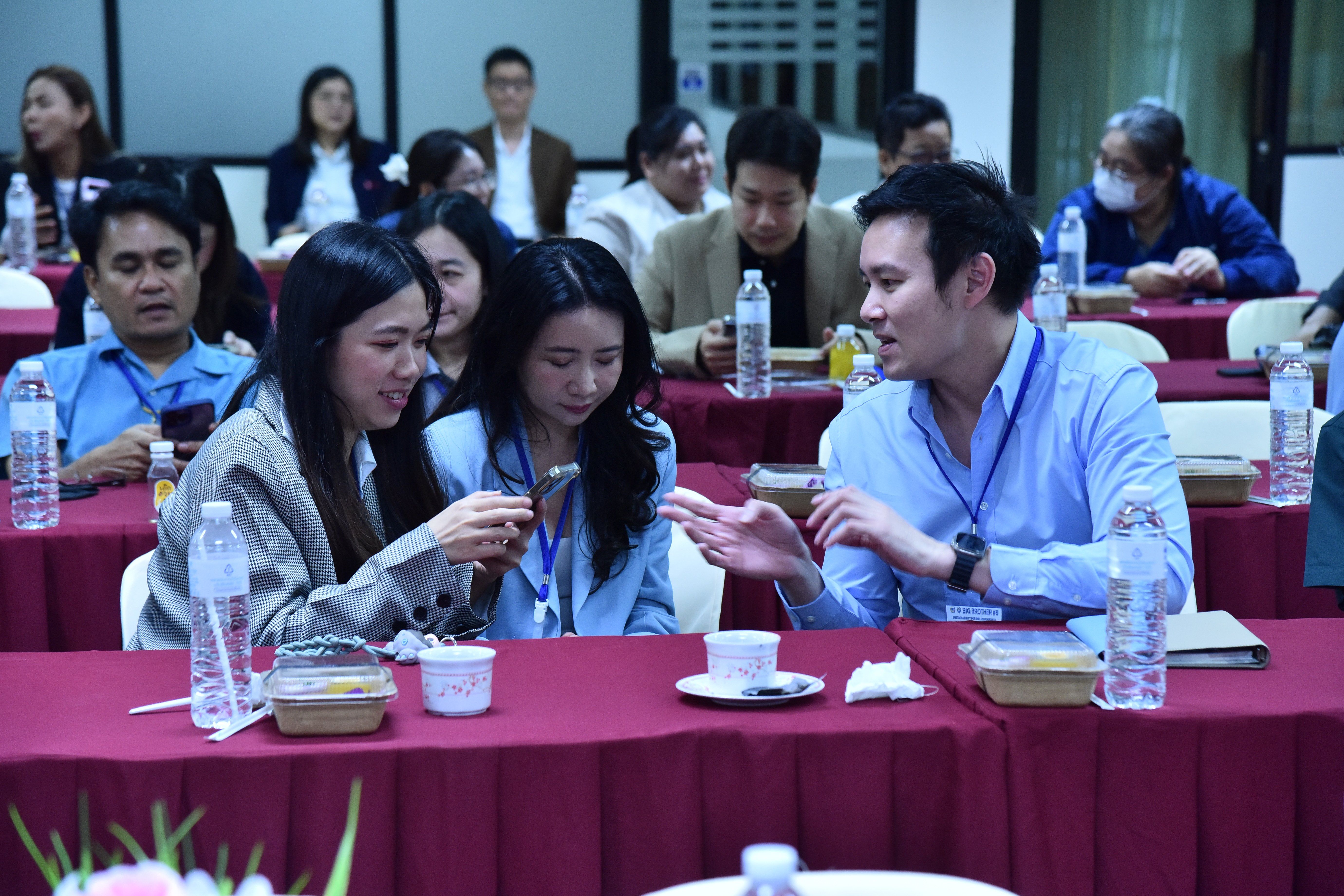 Three colleagues engaged in a discussion at a conference table with refreshments.