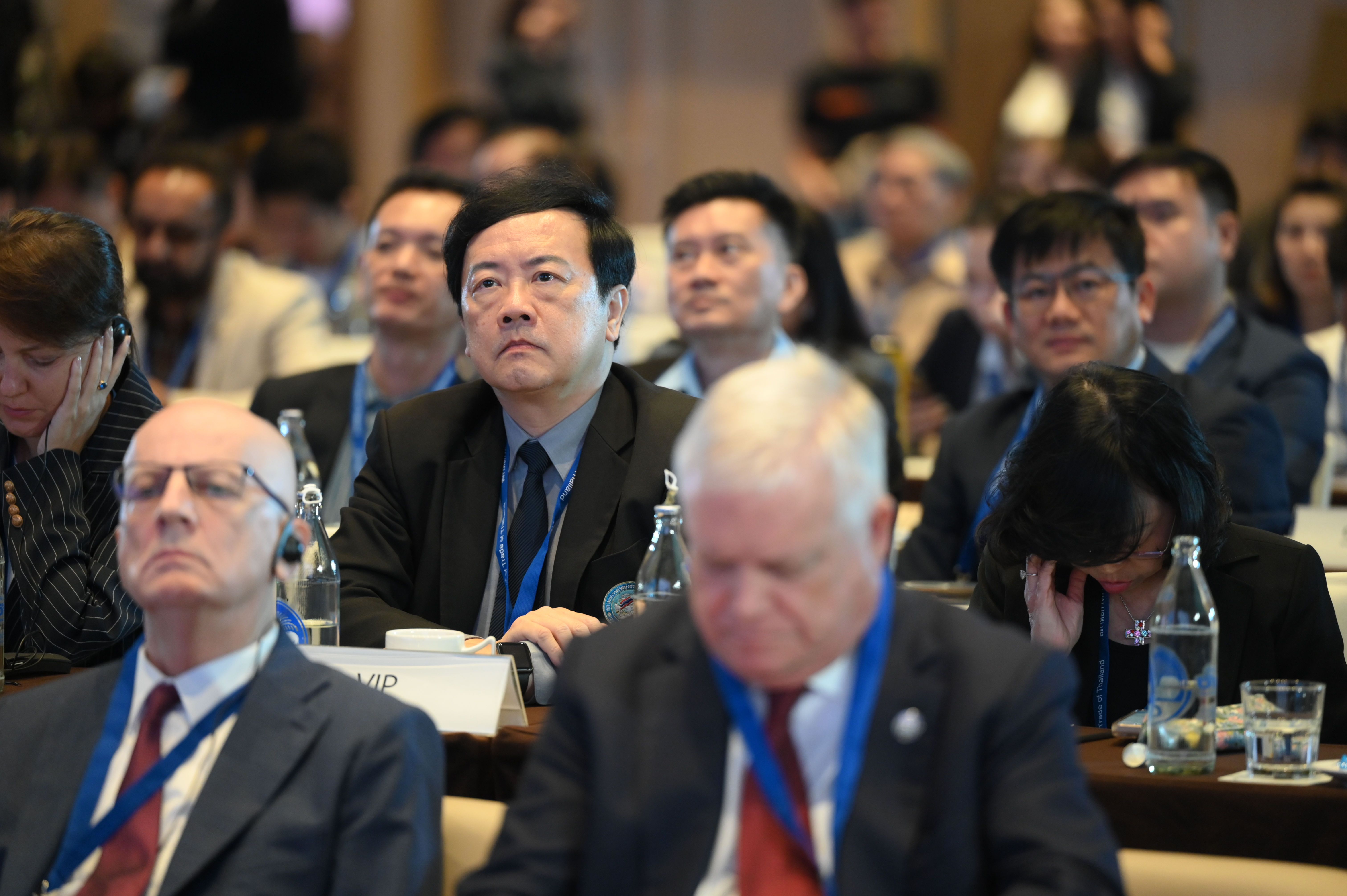 Diverse audience members attentively watching a presentation at a professional conference event.