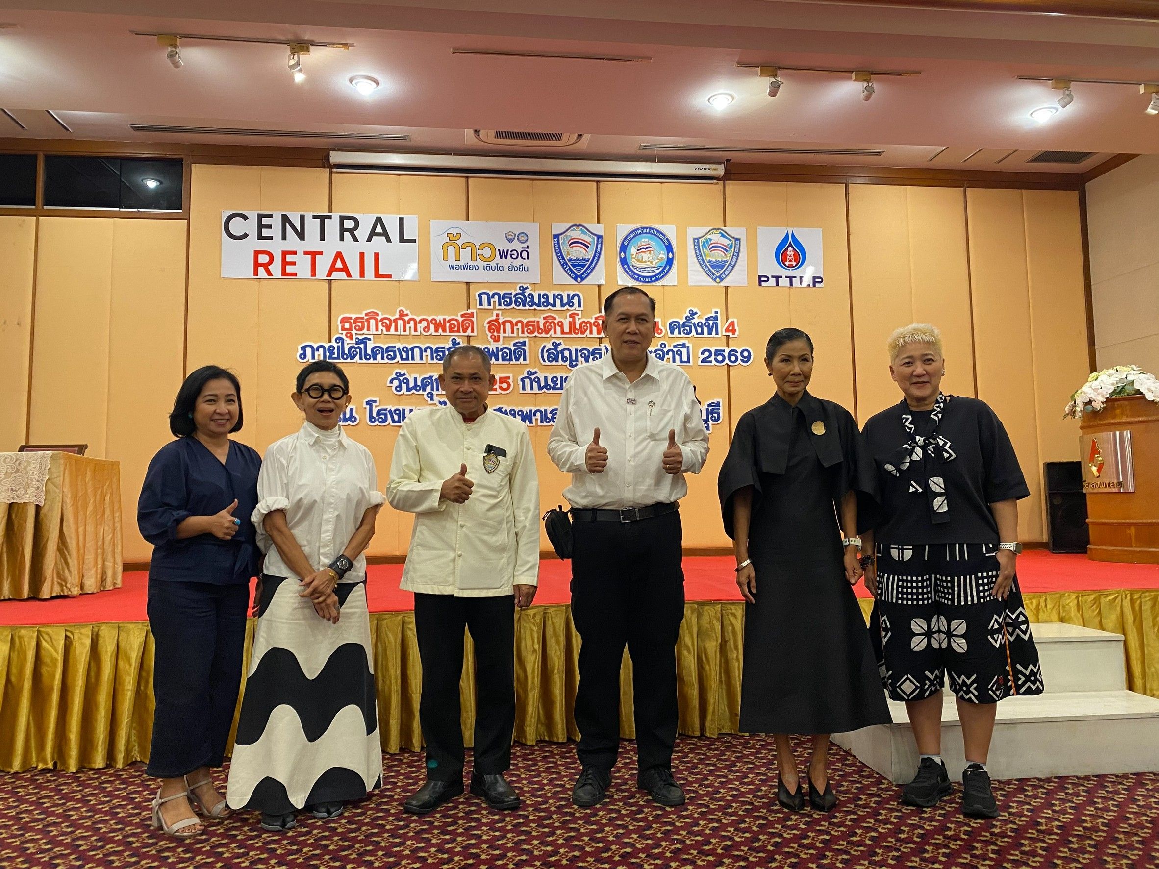 Six people, including two men giving thumbs-up, pose in front of a 'Central Retail' banner.
