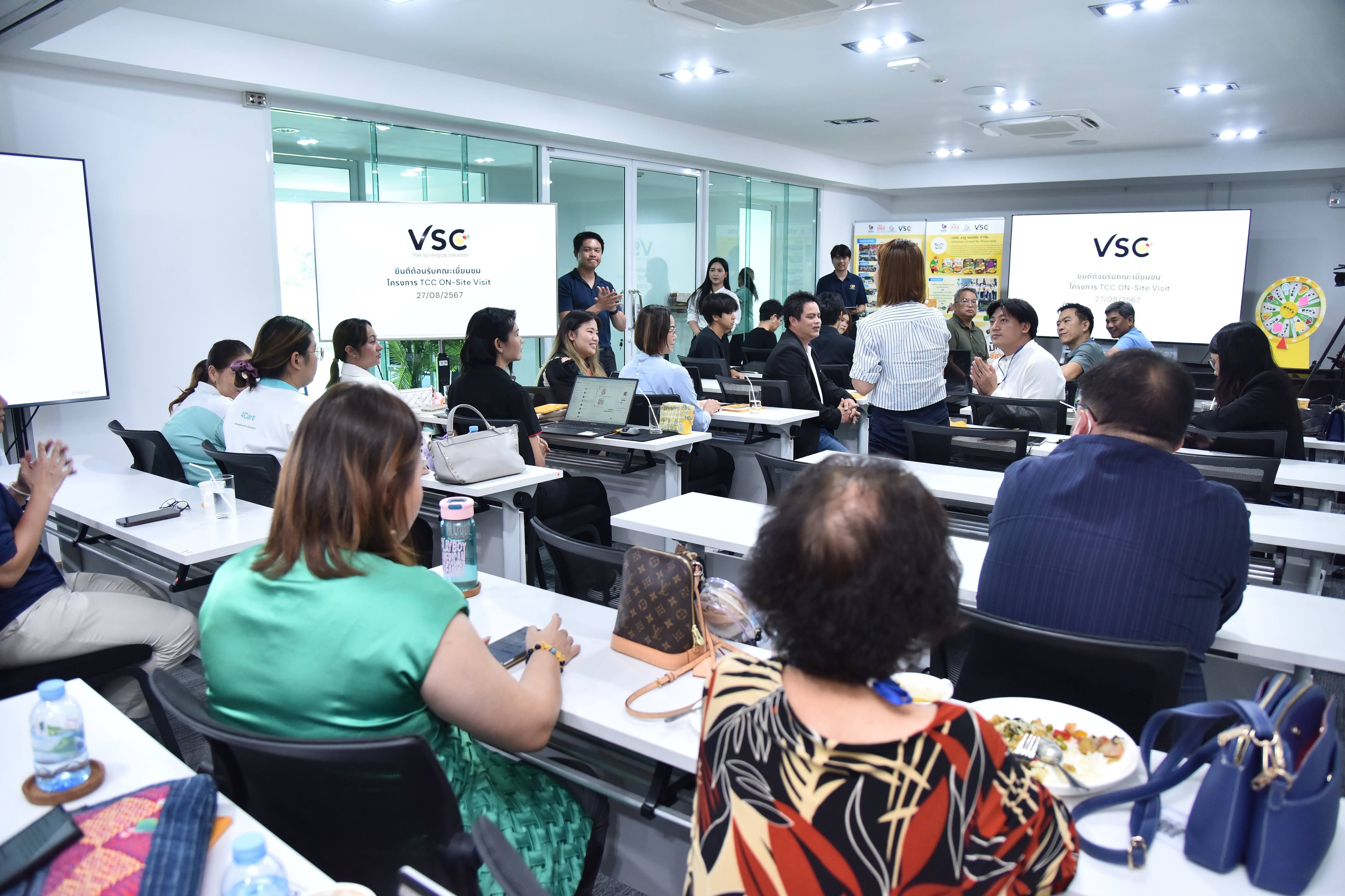 Professionals attend a VSC seminar in a well-lit conference room with presentation screens.