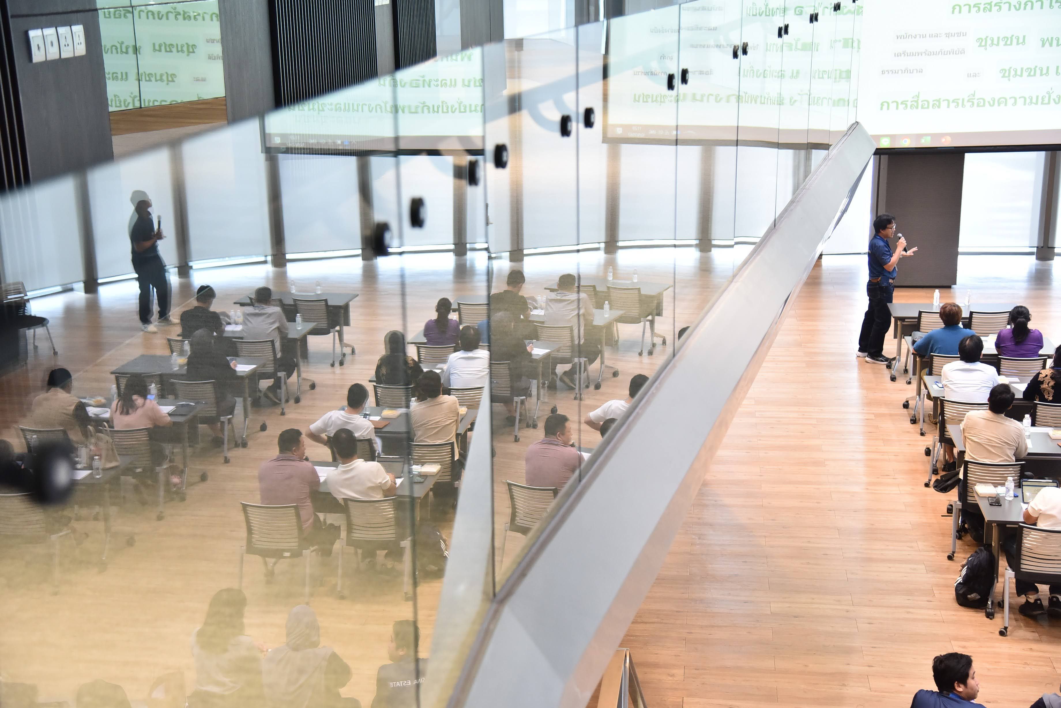 Attendees in a modern, multi-level classroom with a lecturer presenting.