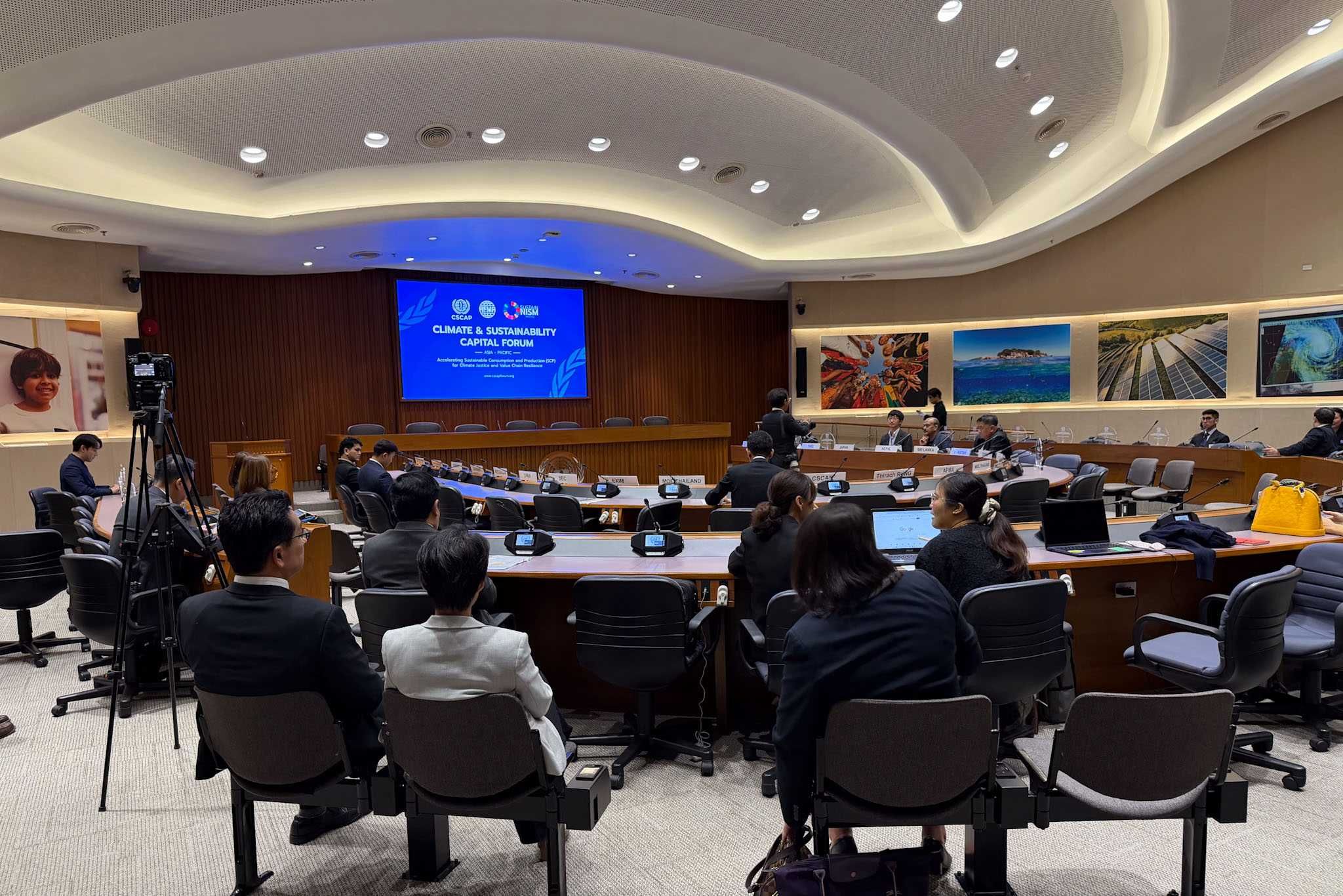 Attendees seated in a conference room facing a screen displaying 'Dialogue on Migration'.