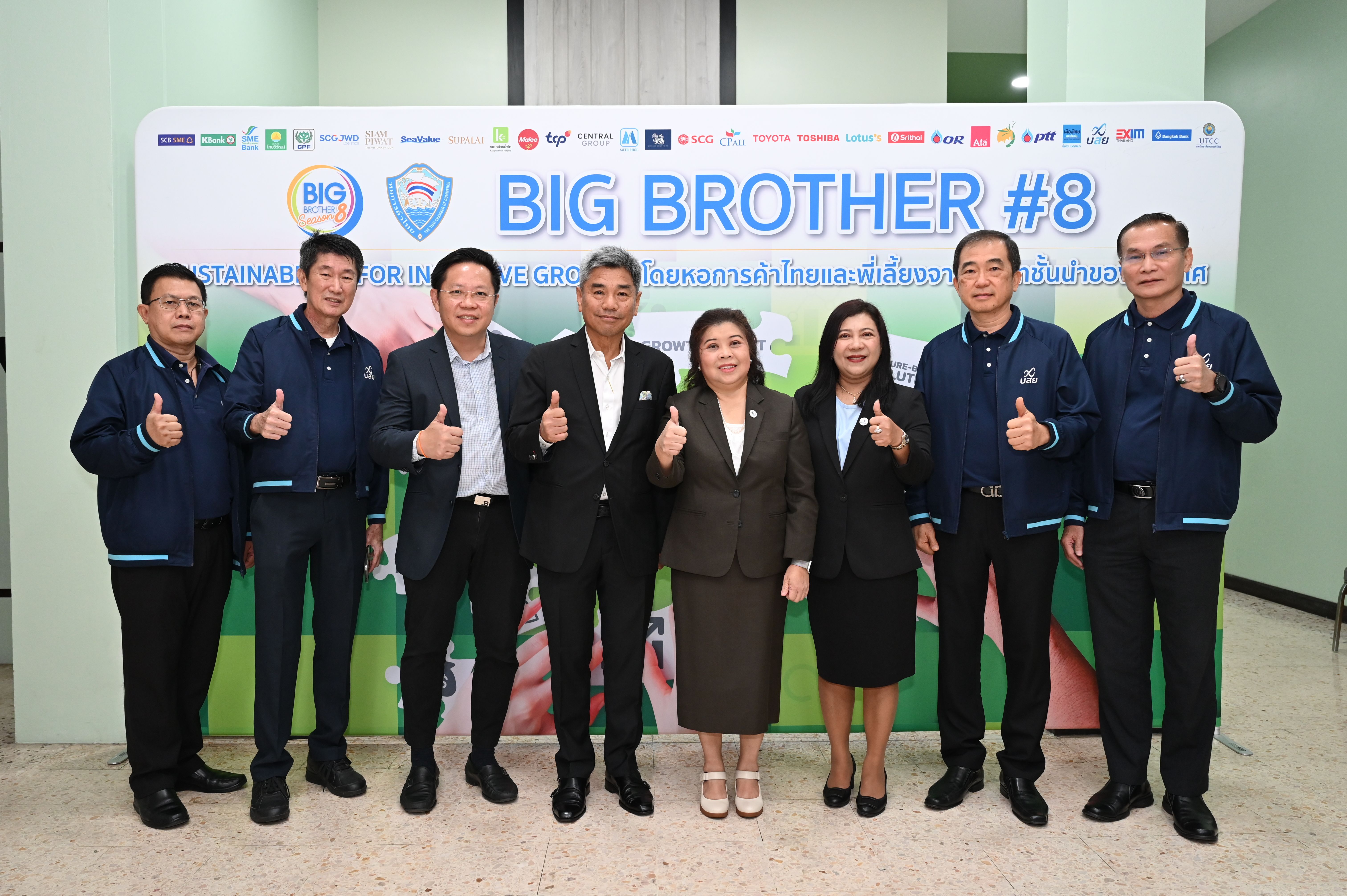 Eight professionals giving thumbs up in front of a "BIG BROTHER #8" event banner.