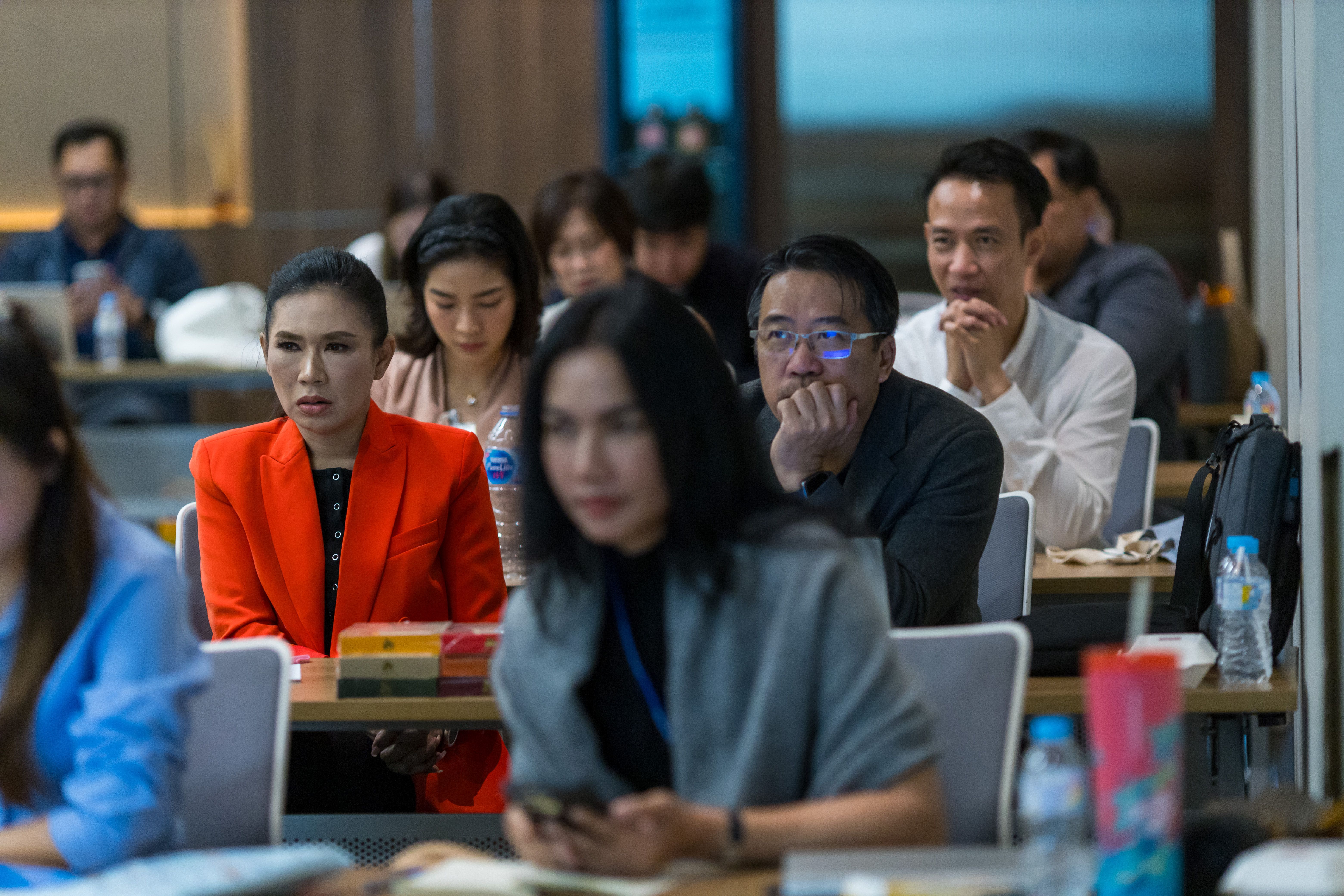 Diverse group of professionals attentively listening in a modern conference room setting.