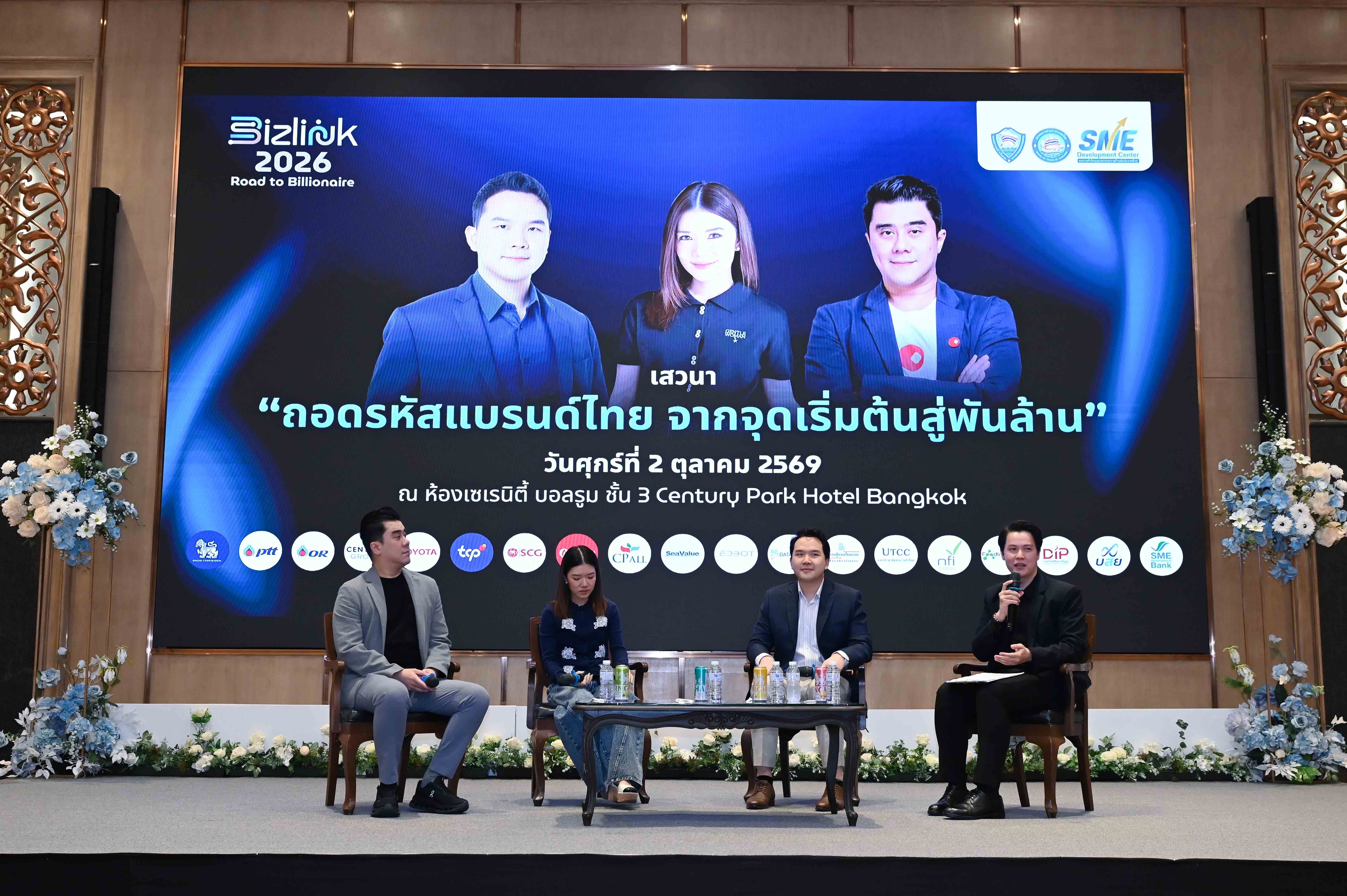 Four panelists on stage with a large screen displaying event details and speaker portraits.