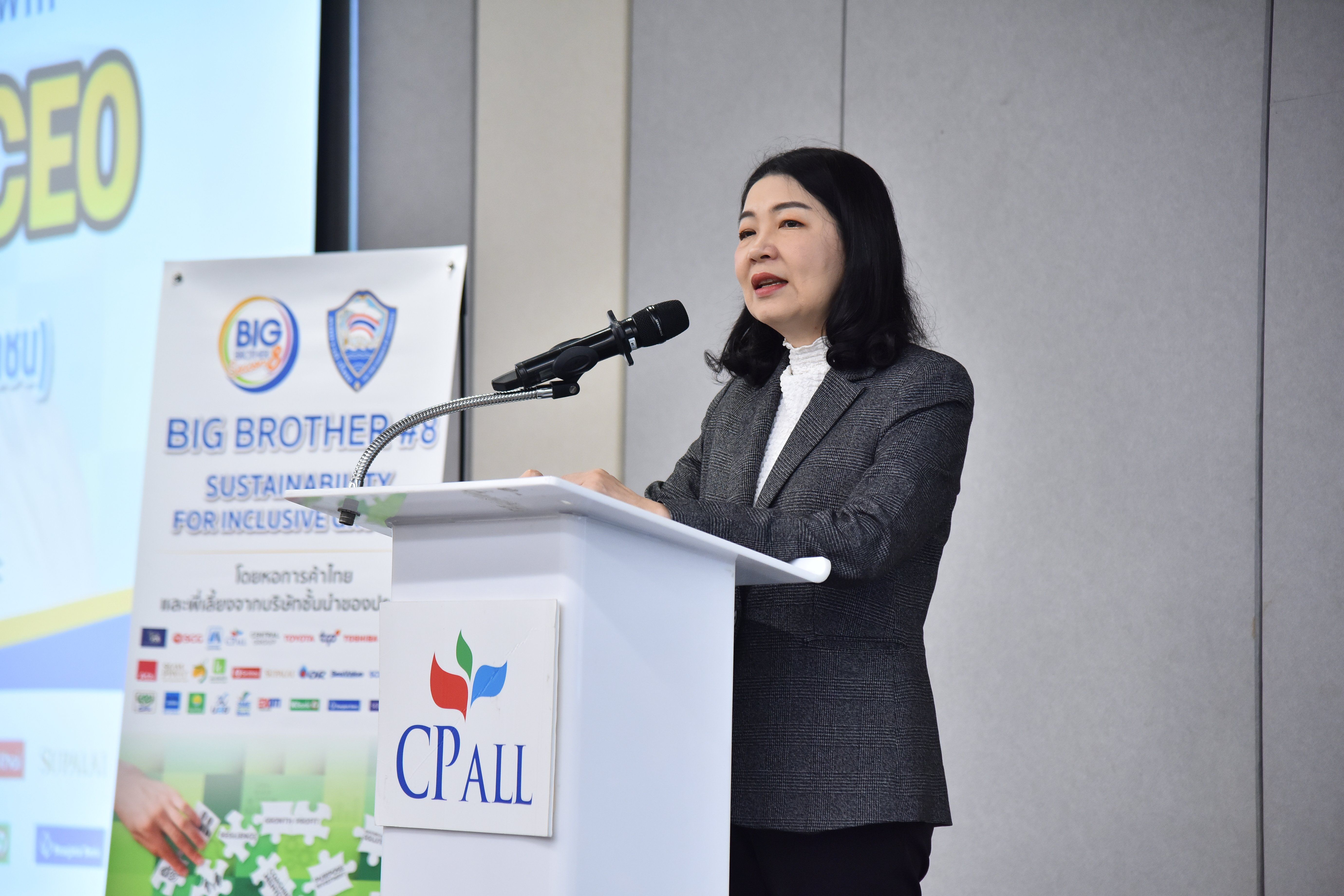 A woman in a suit speaks at a podium with CP ALL branding during a corporate event.