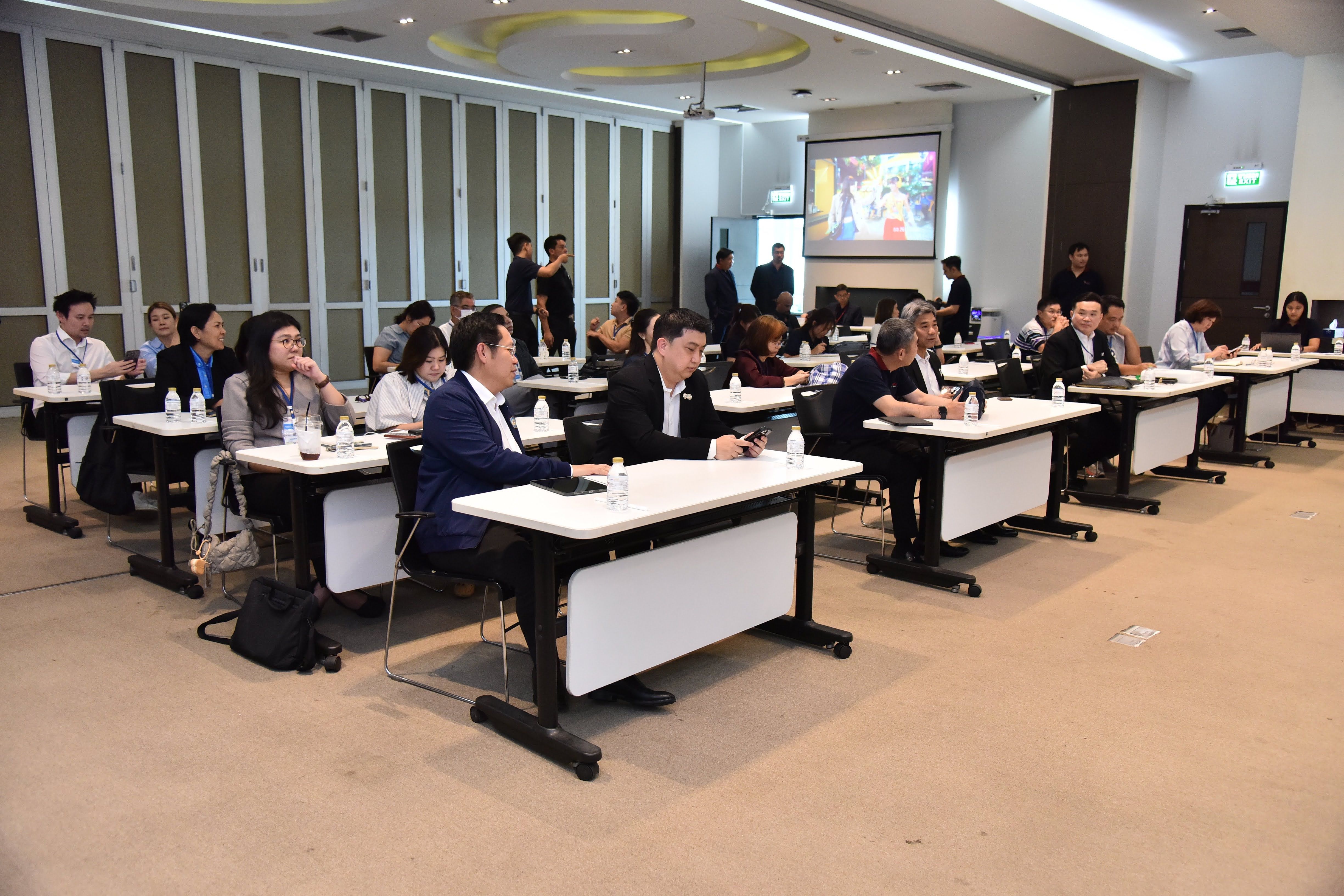 Professionals attend a presentation in a modern conference room with a projector screen.