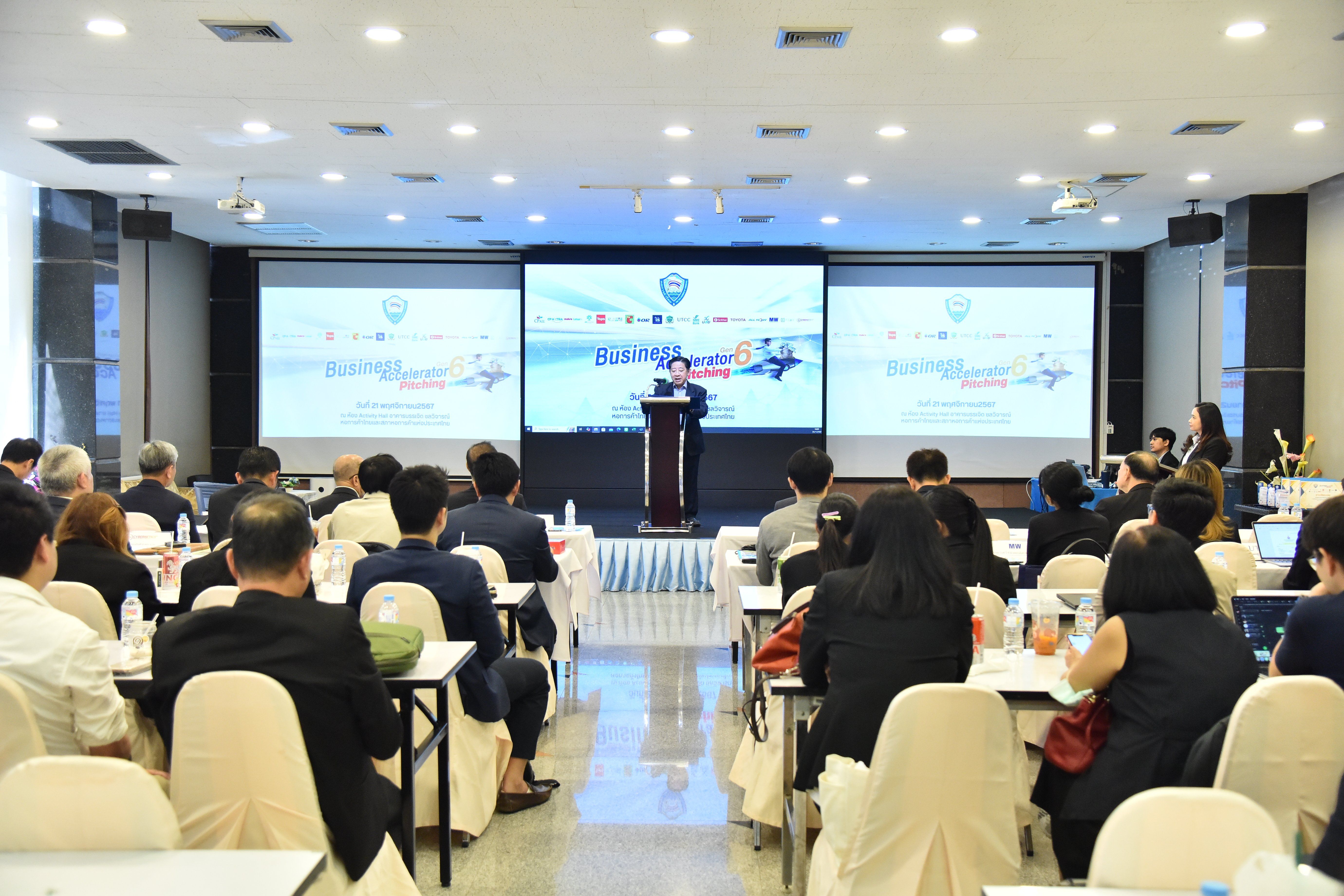 Speaker presents to an attentive audience in a conference room with three large screens.