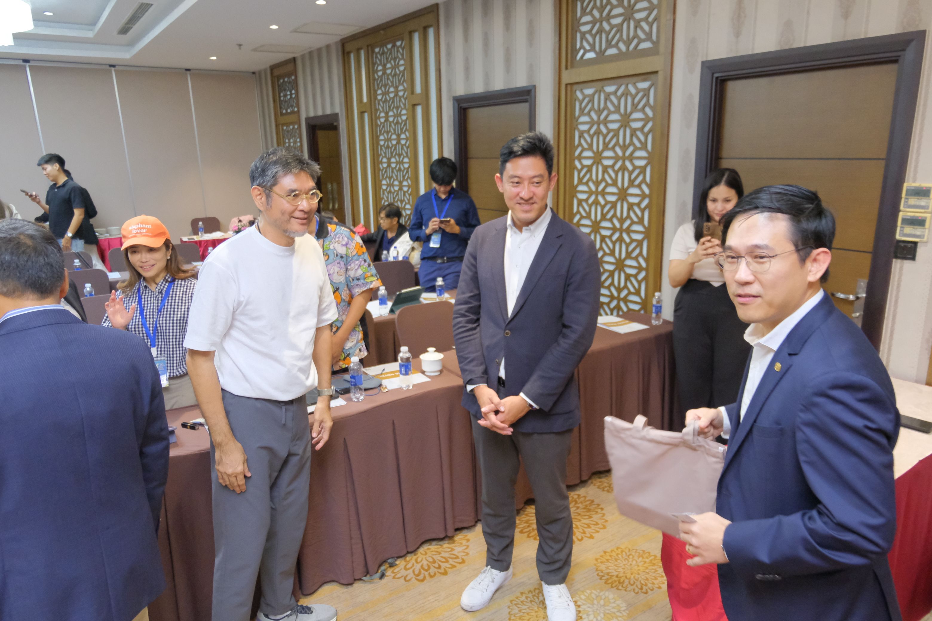 Three men in business casual attire are smiling and conversing in a modern conference room.