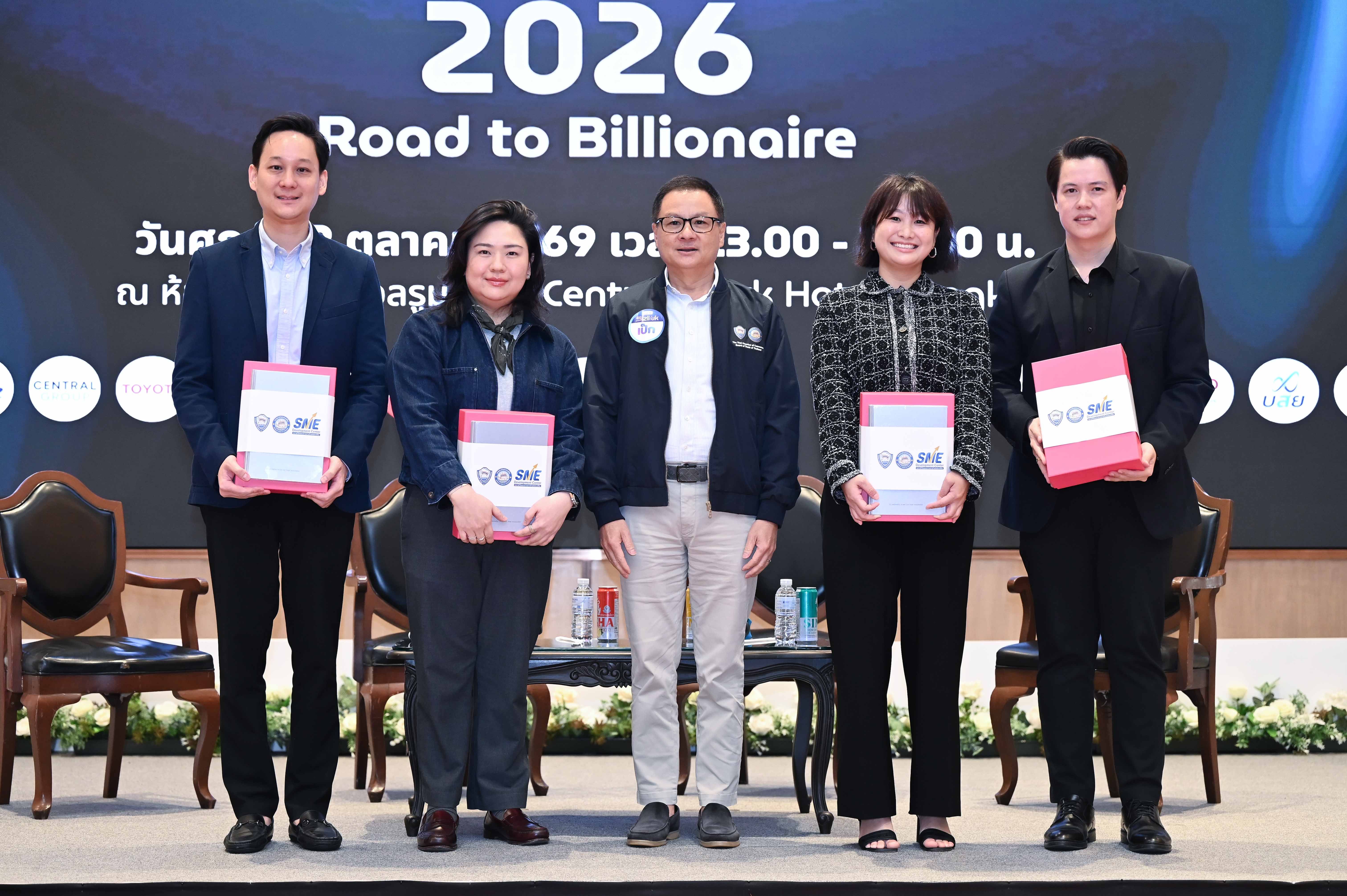 Five professionals holding red folders on a stage with a '2026 Road to Billionaire' banner.