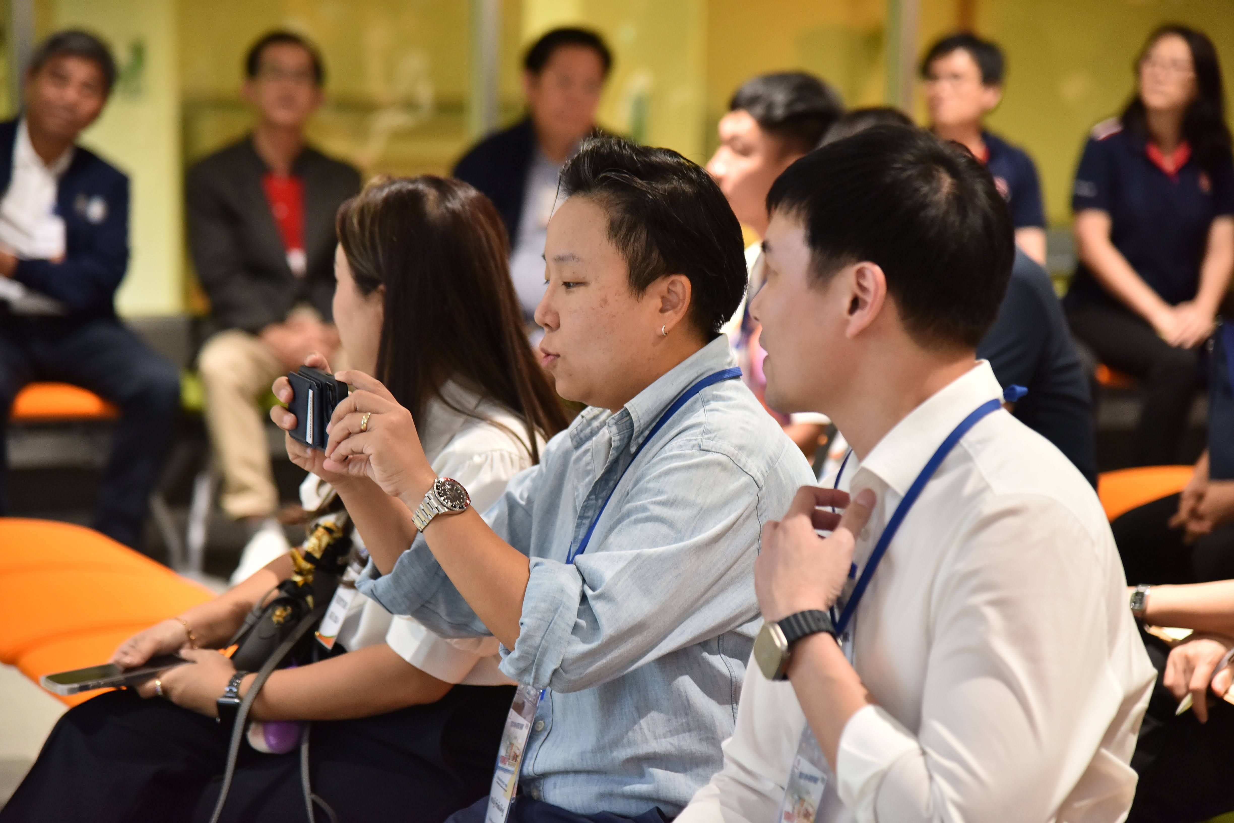 Attendees at a conference ask questions using microphones during an interactive session.