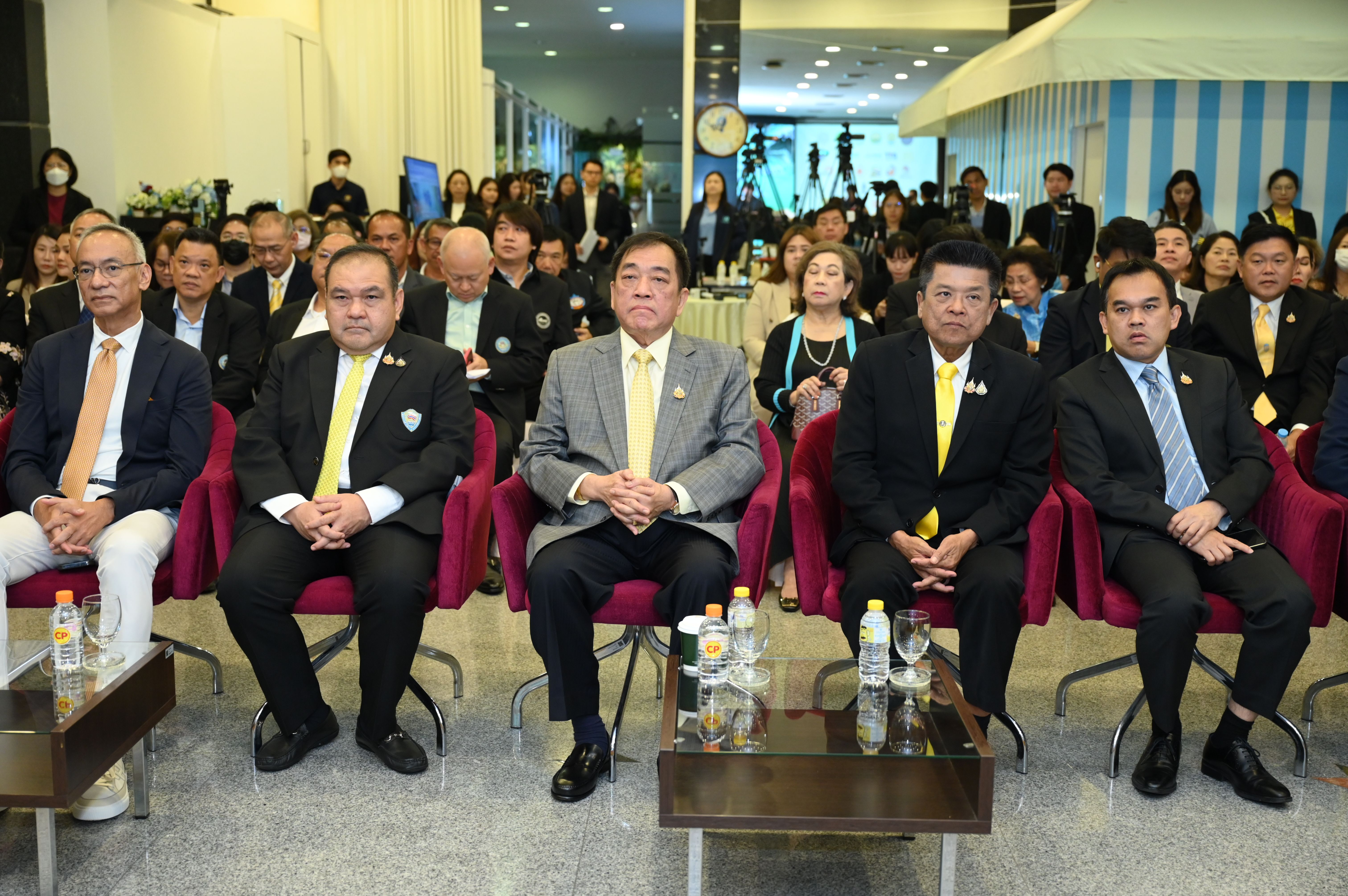 Group of formally dressed men sitting in the front row at a large indoor event.