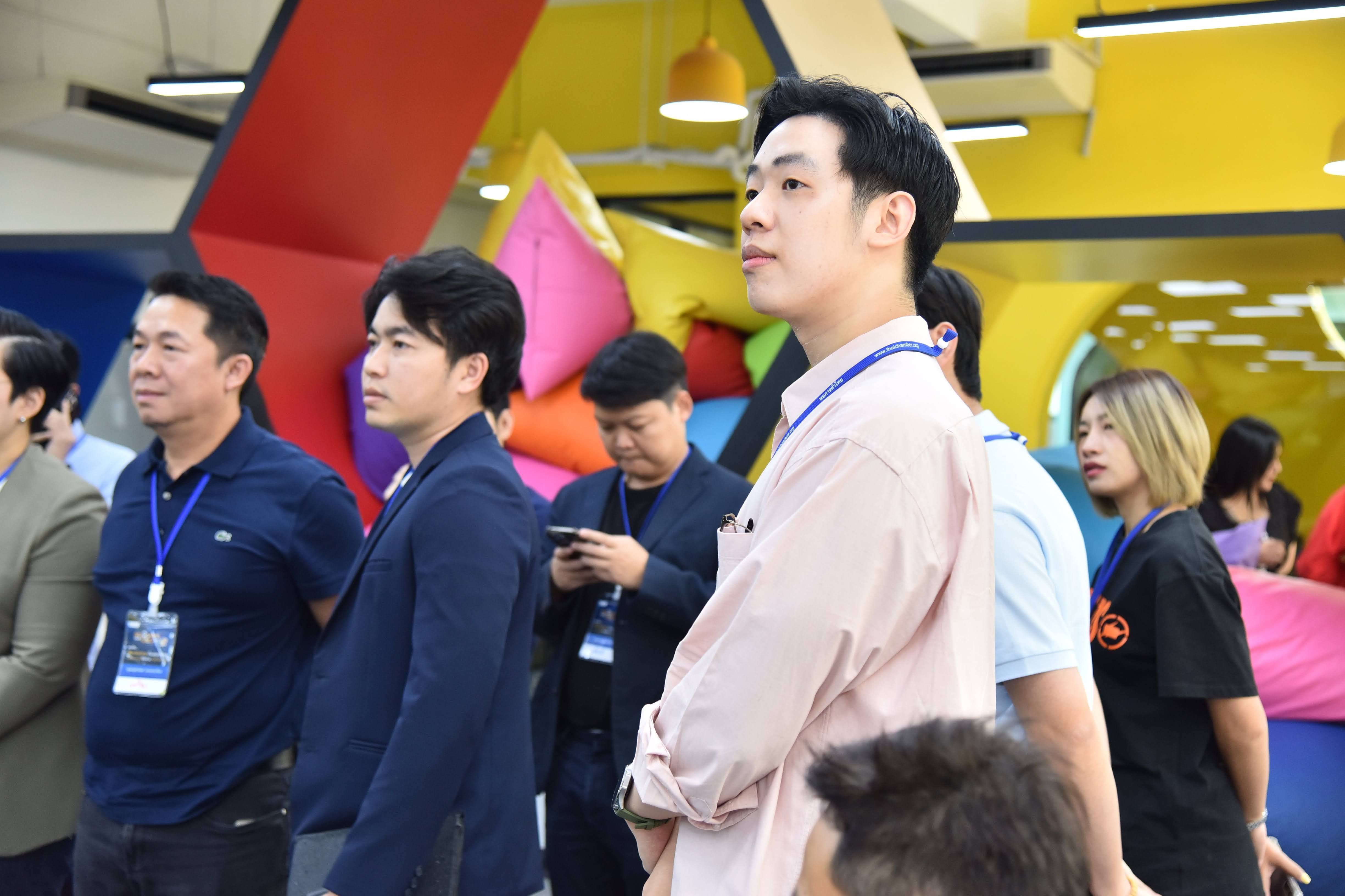 Man in pink shirt looking intently, surrounded by other attendees at an event.