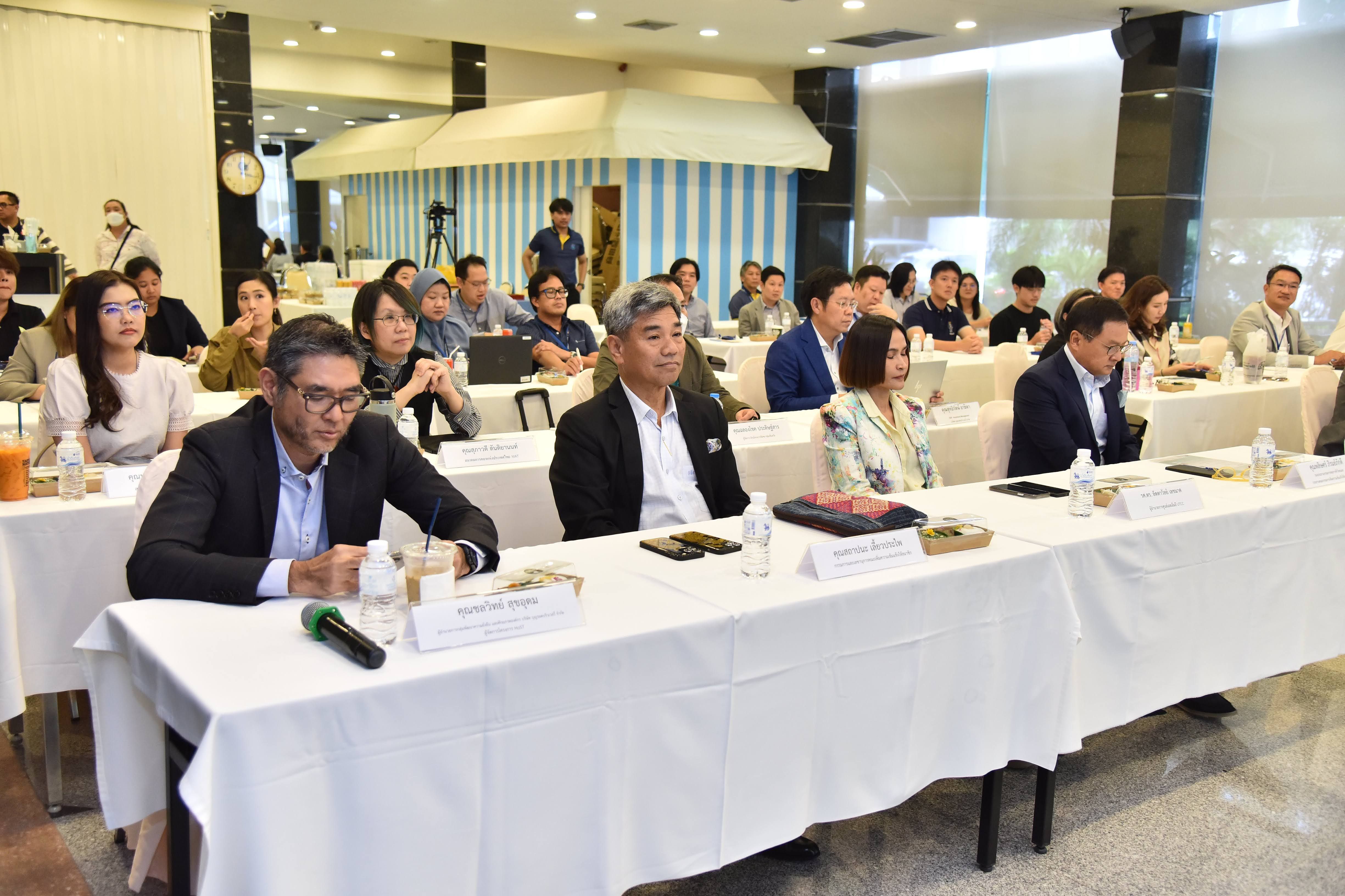 Professionals attend a conference, seated at white-clothed tables in a brightly lit room.