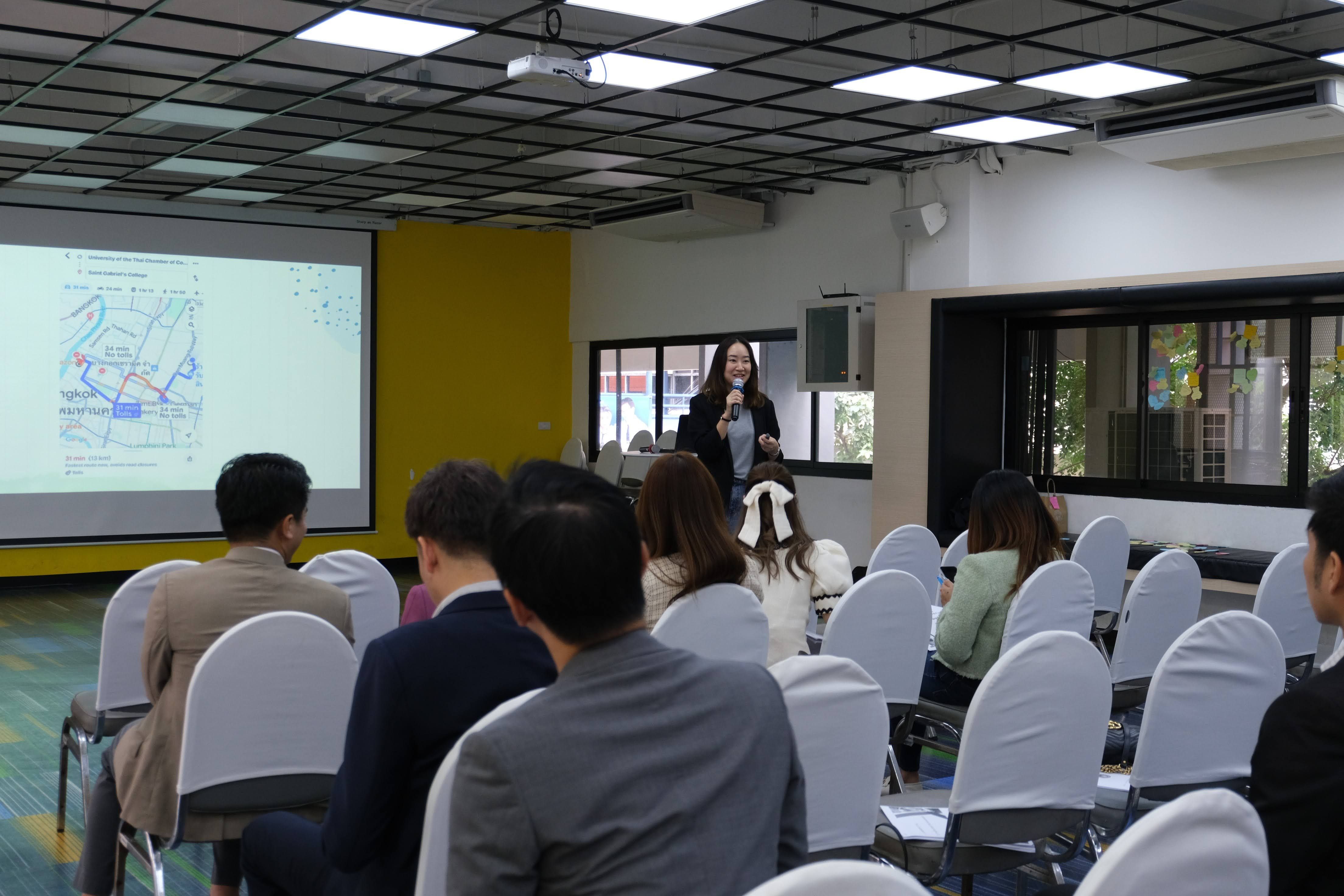 Professional woman presenting to an audience with a diagram on a projector screen.