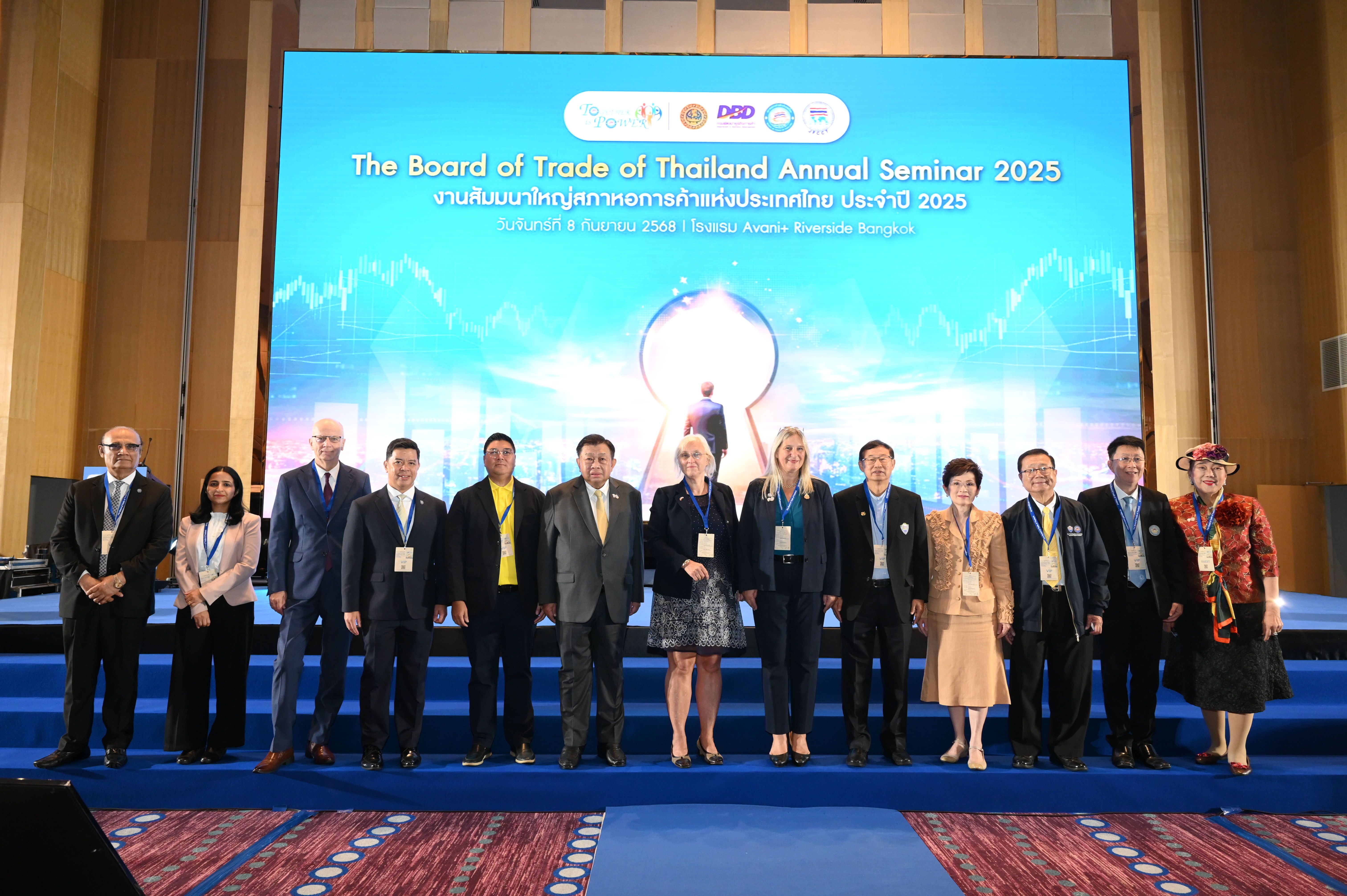 Professionals stand on stage before a screen for the Board of Trade of Thailand seminar.