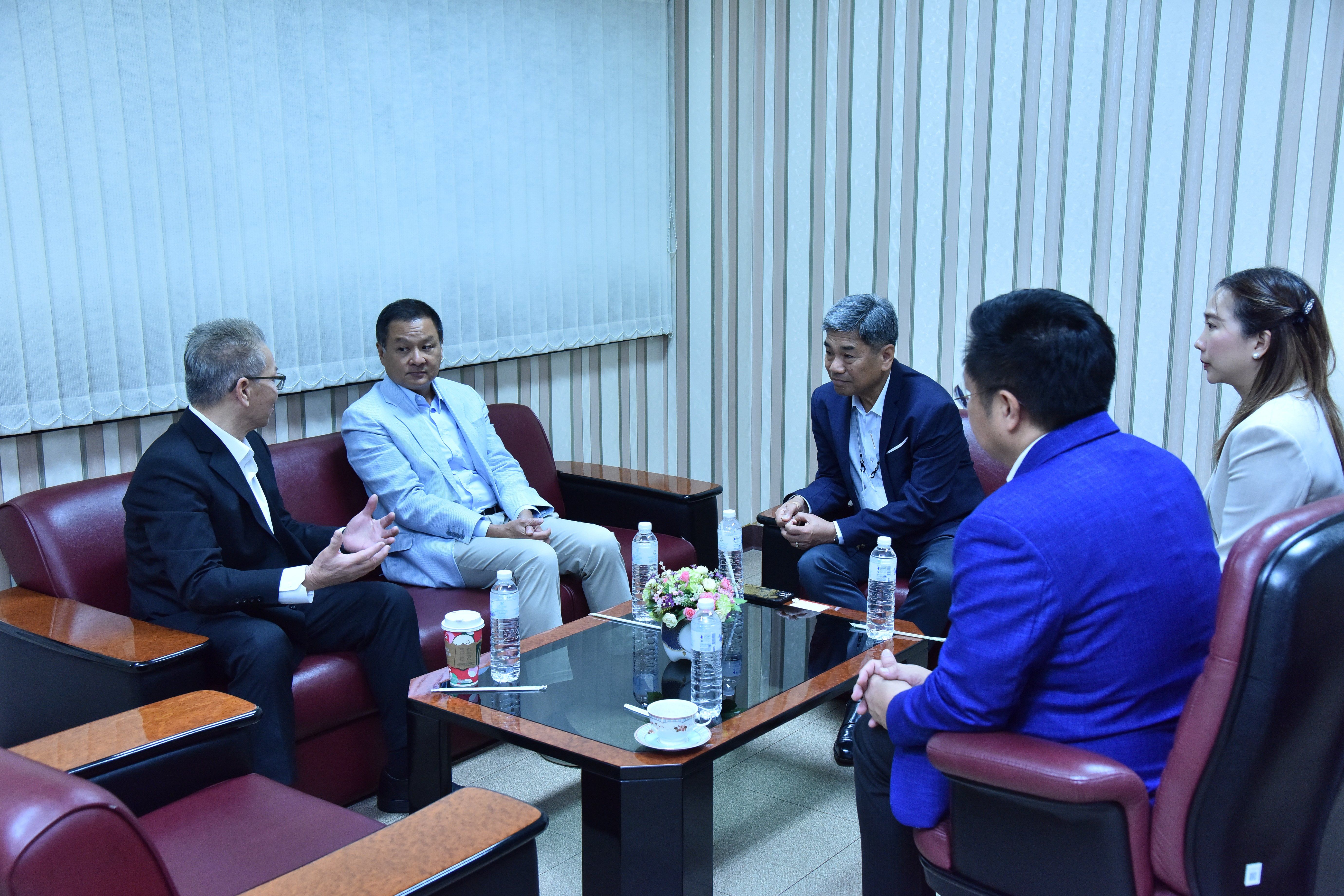 Five professionals, three men and two women, meet in a conference room discussing business.