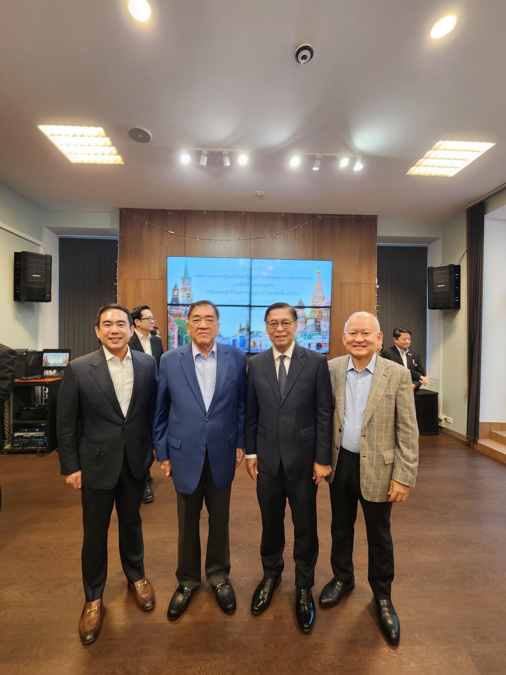 Four professional men smiling, standing together in an event room.