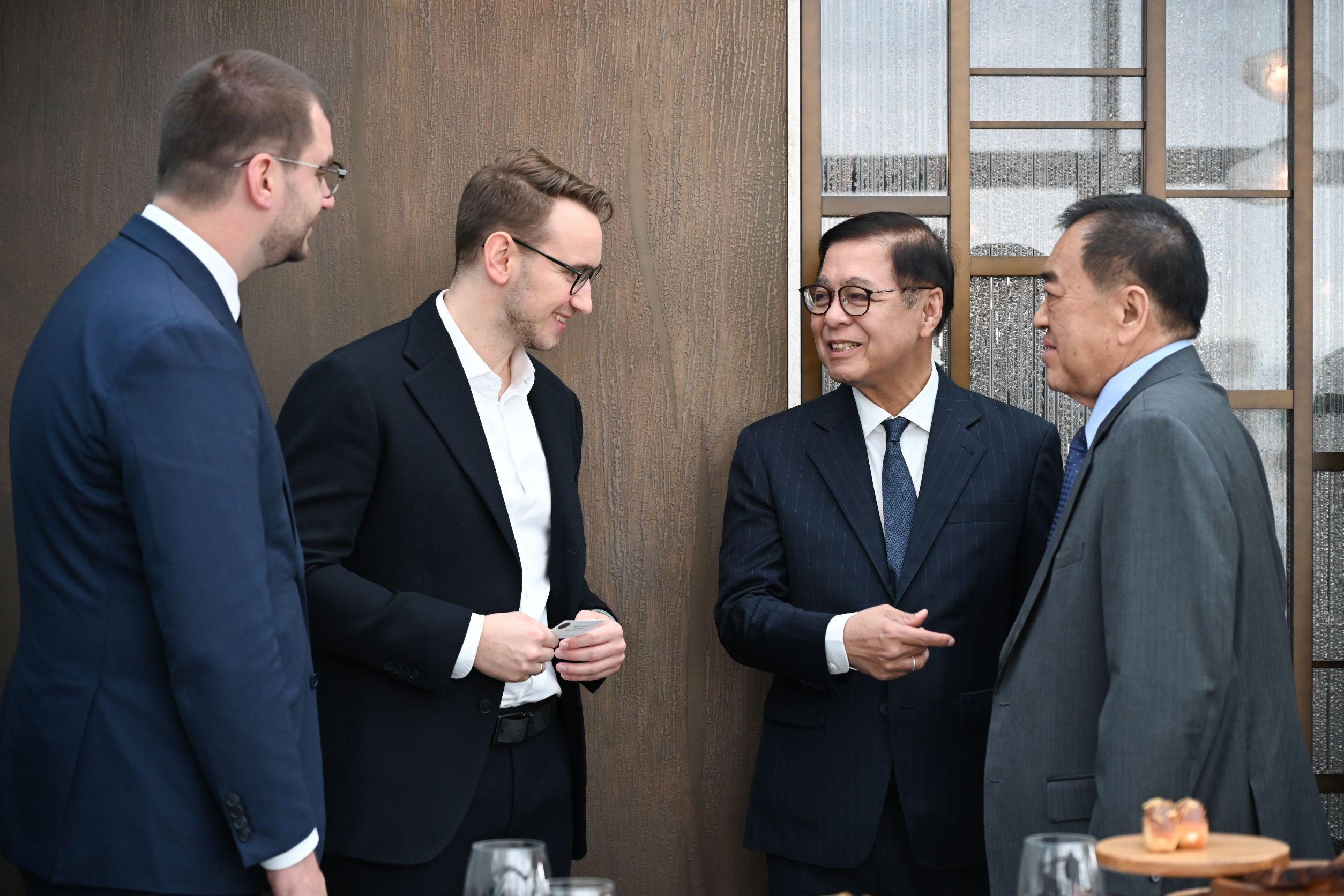 Four diverse businessmen in suits engaged in a serious discussion at a formal event.