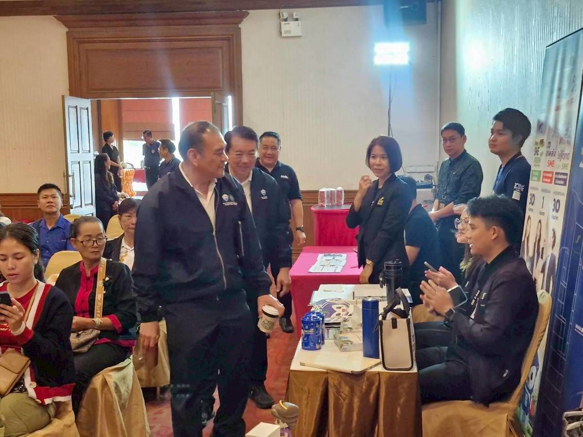 A man in a dark tracksuit walks through a crowded indoor event, greeted by attendees.