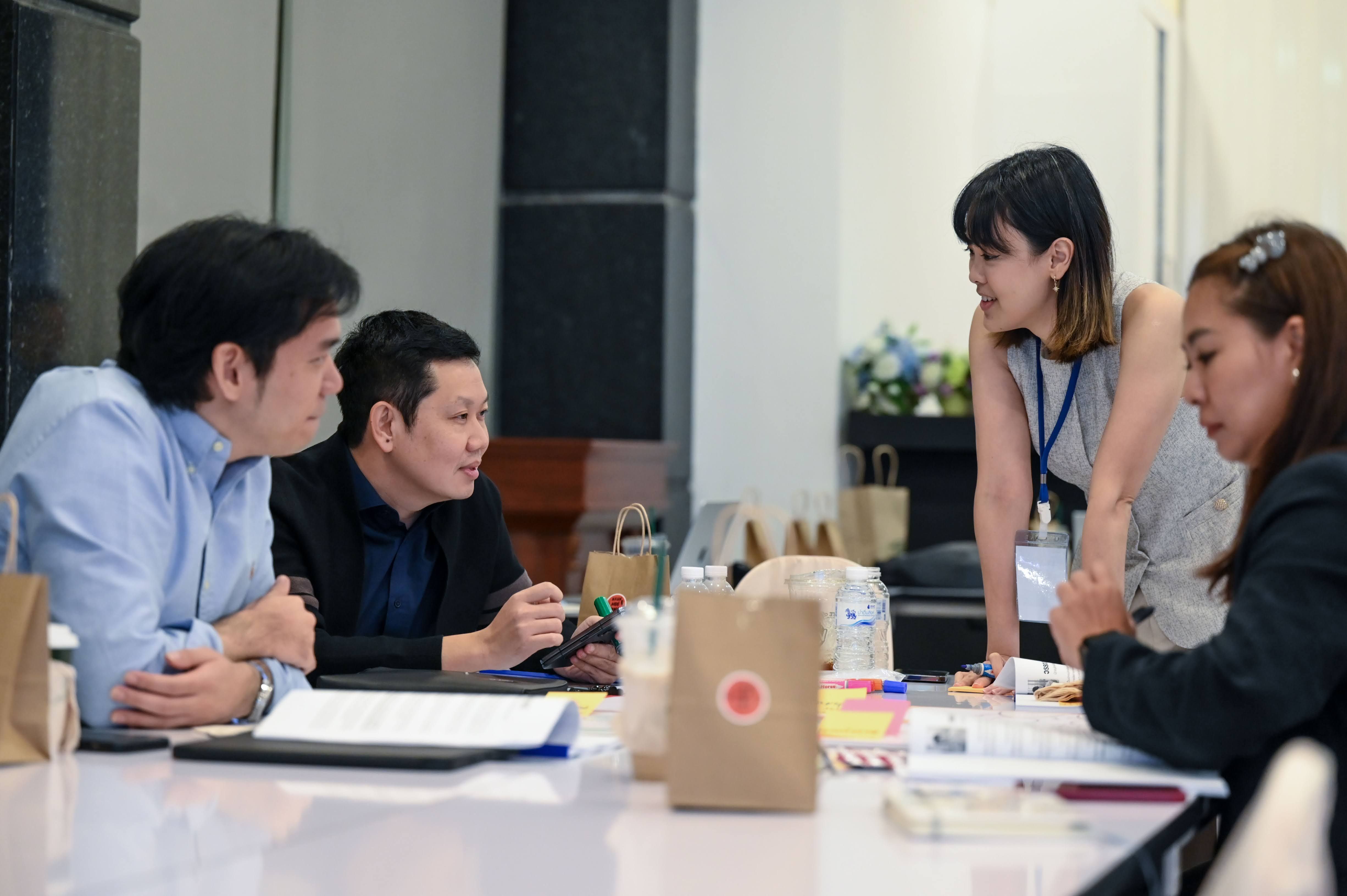 Four professionals discussing at a table during a collaborative meeting.