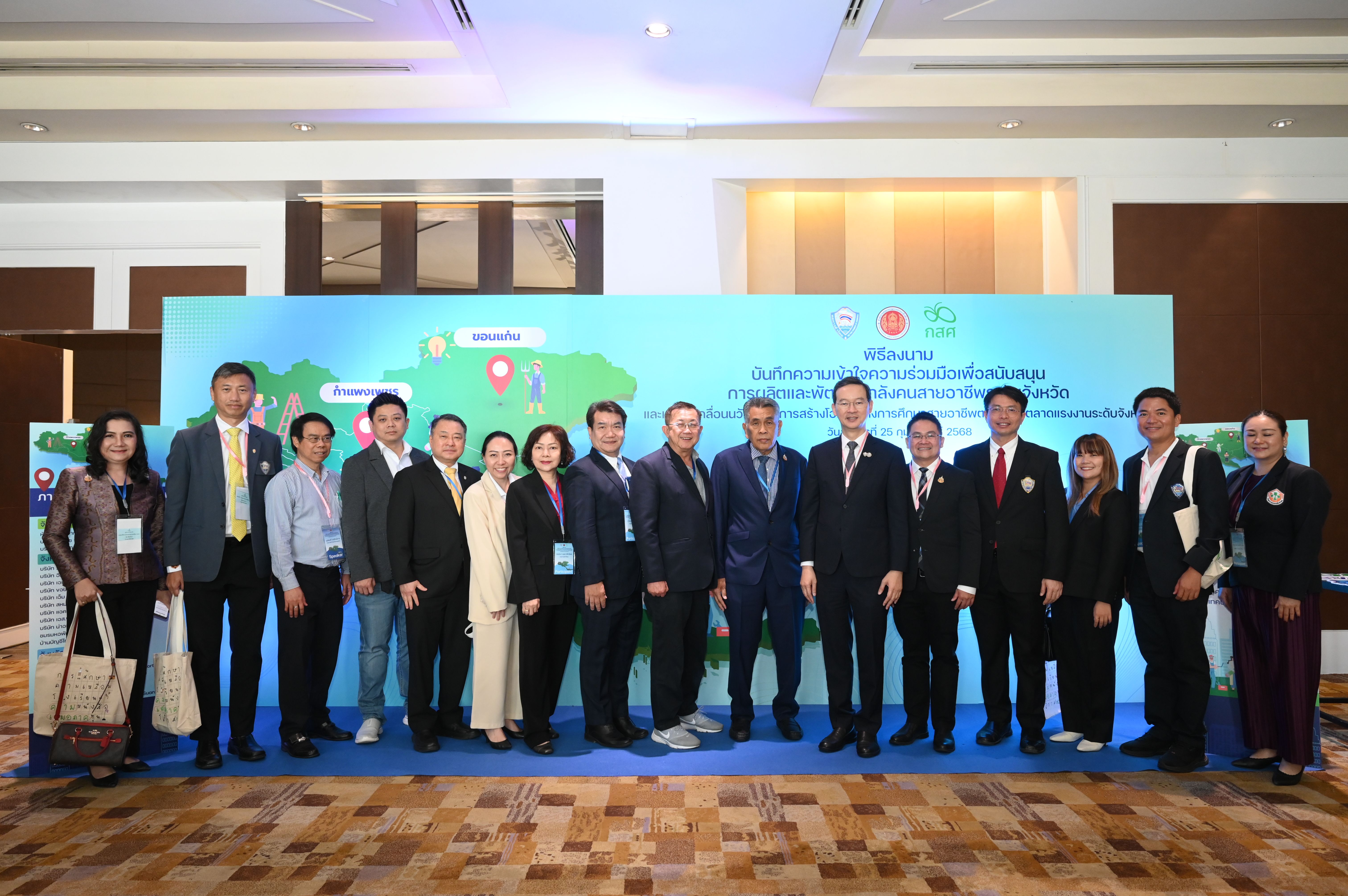 A group of professionals stands in front of a blue banner at an indoor conference event.