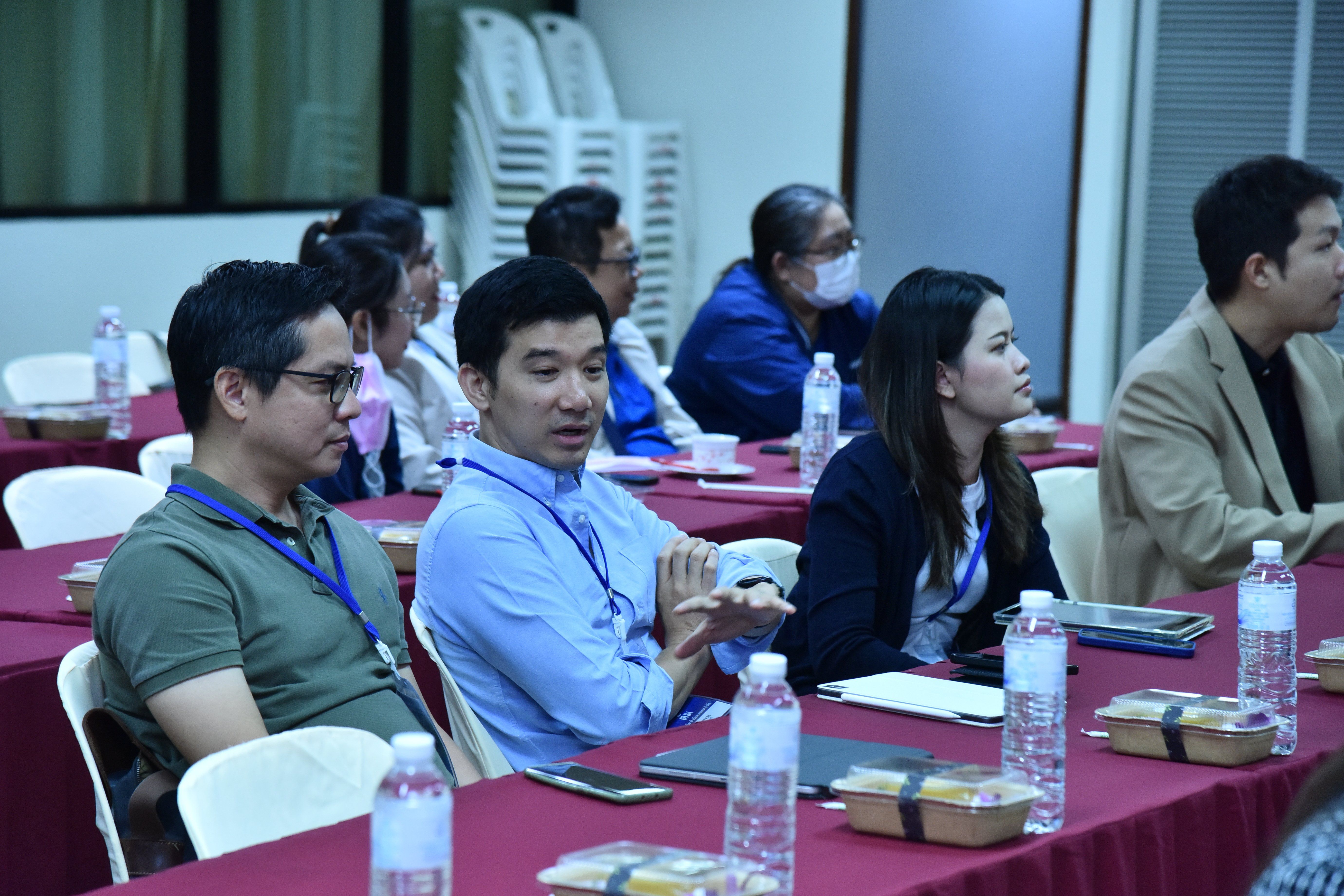 Professionals seated at tables in a meeting, attentively listening to a presentation.