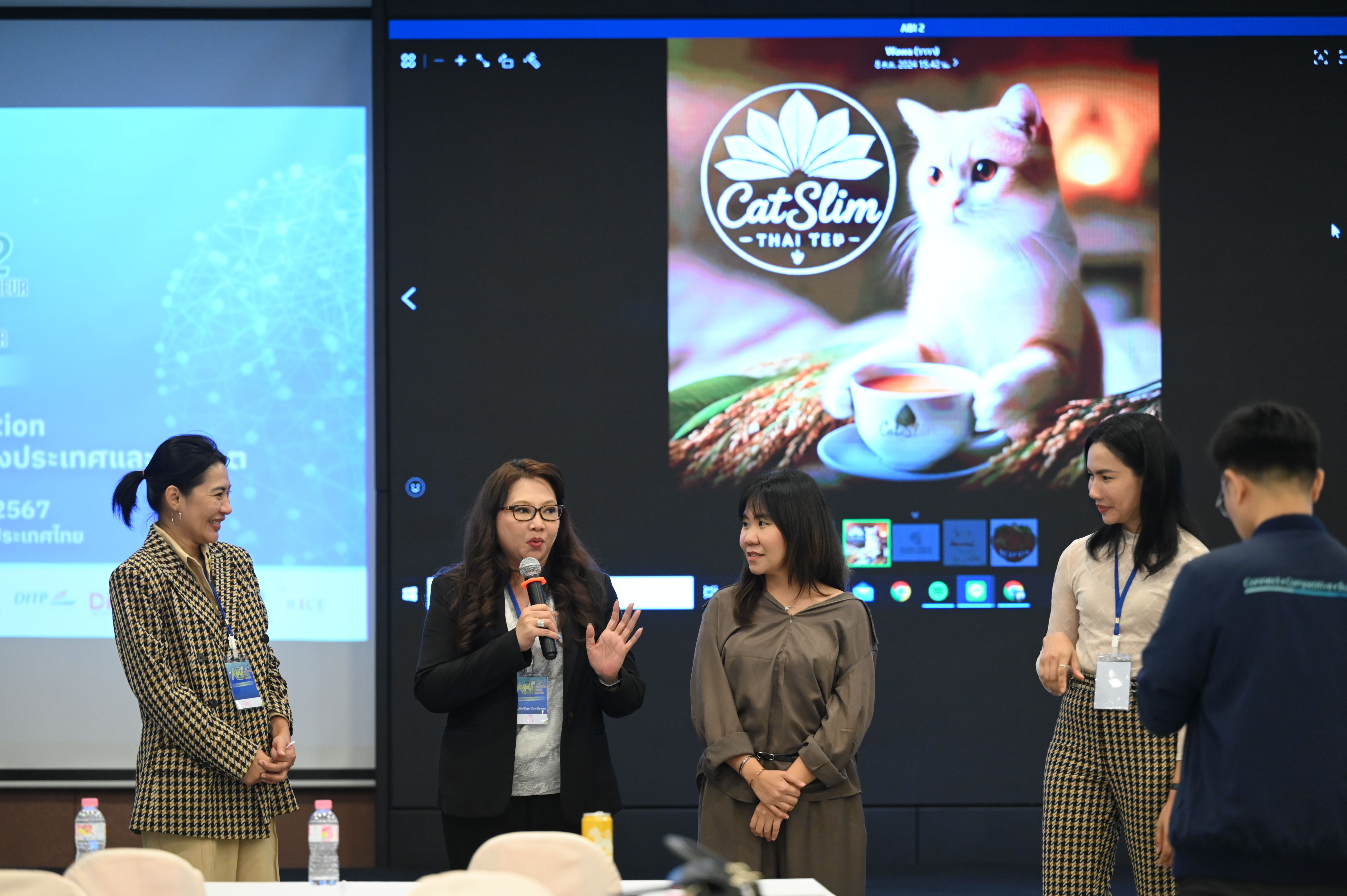 Woman speaks at conference, large screen behind shows 'Cat Slim' cat and coffee ad.
