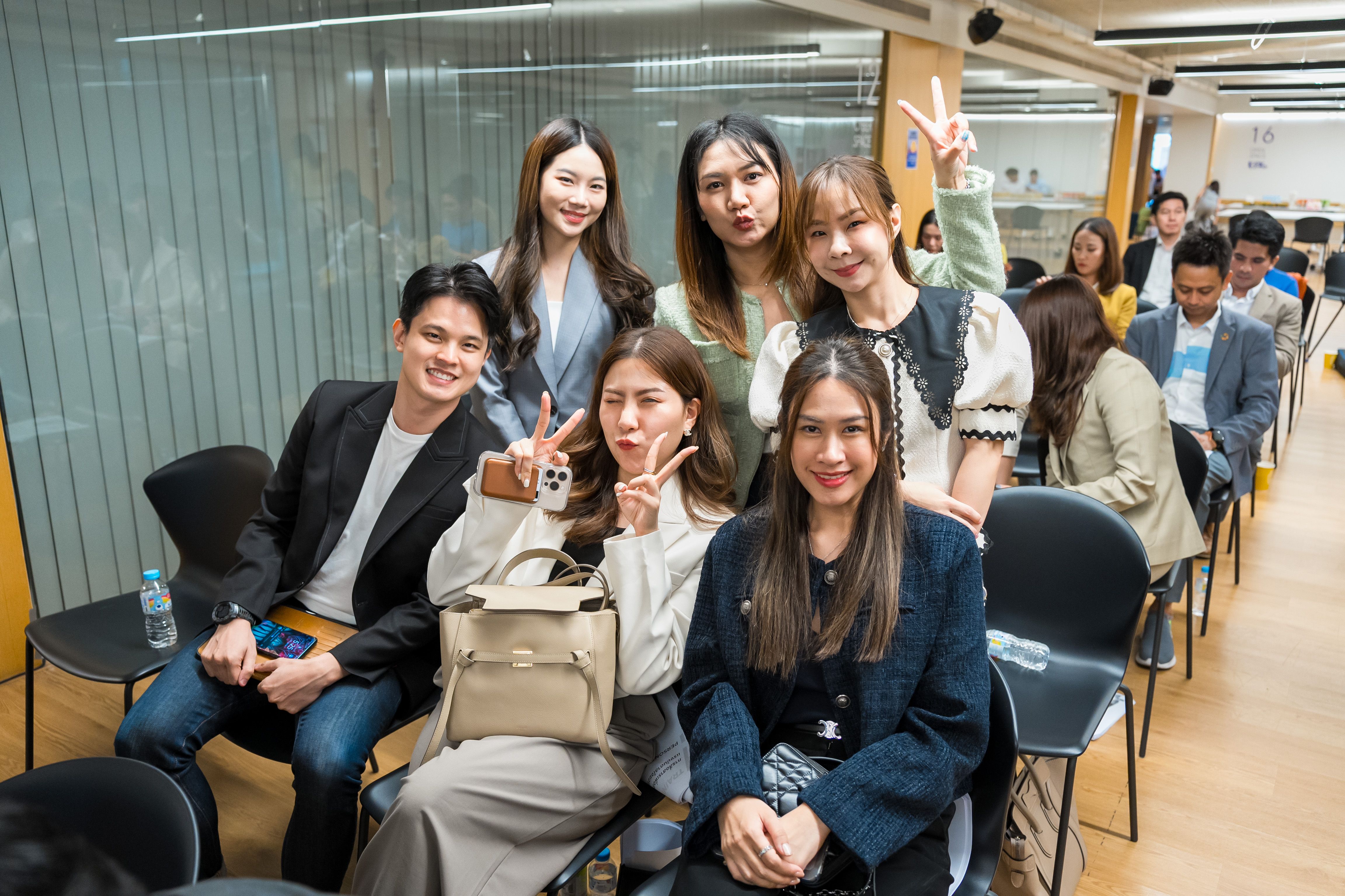 Group of six young professionals smiling and posing with peace signs at an event.