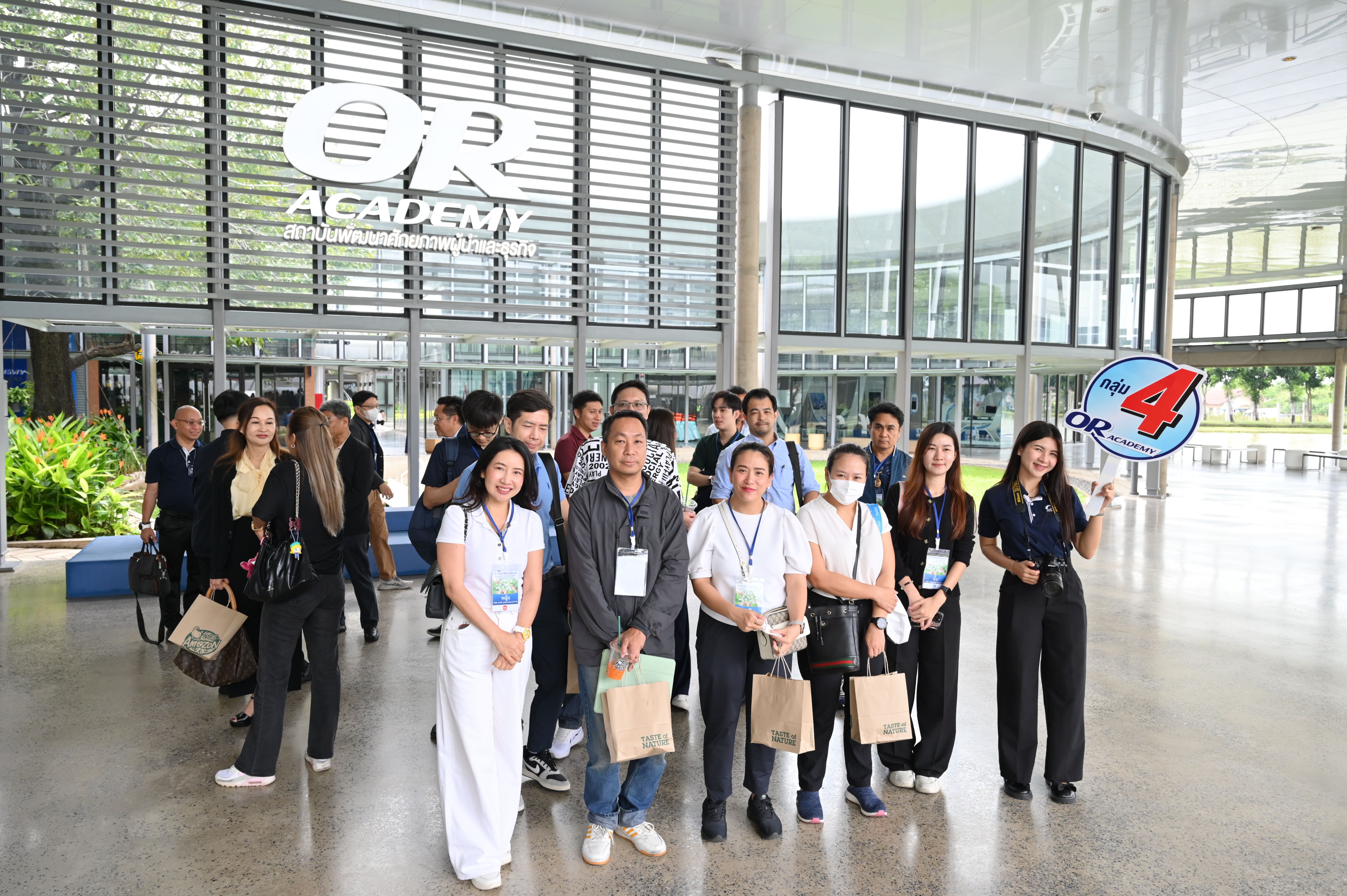 A diverse group of professionals poses outside the modern OR Academy building entrance.