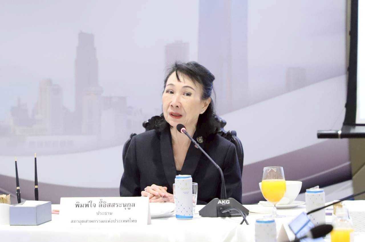 Apiradi Tantraporn speaking at a microphone during a conference with orange juice on table.