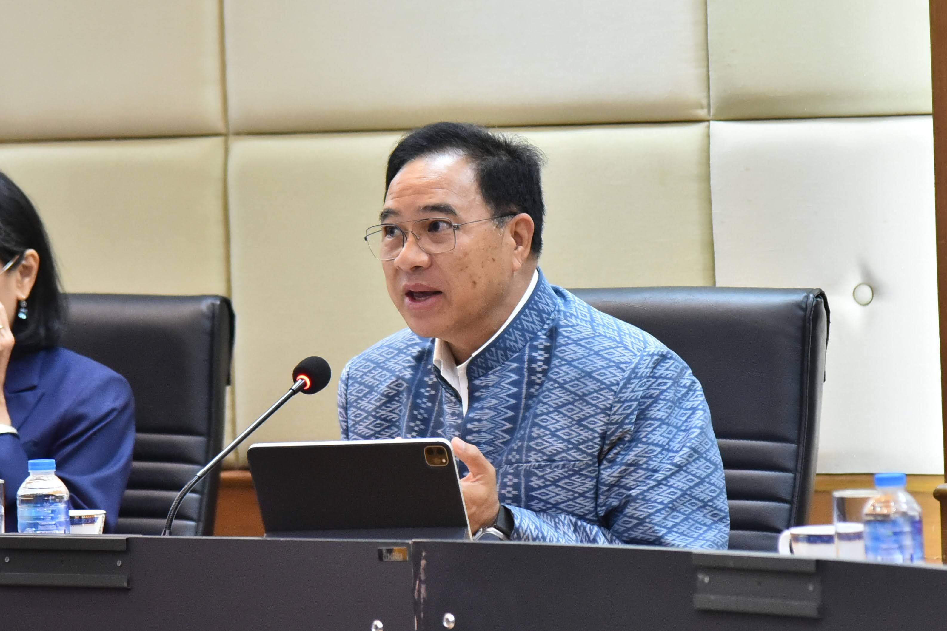 Man in blue patterned shirt speaks at a meeting with a microphone.