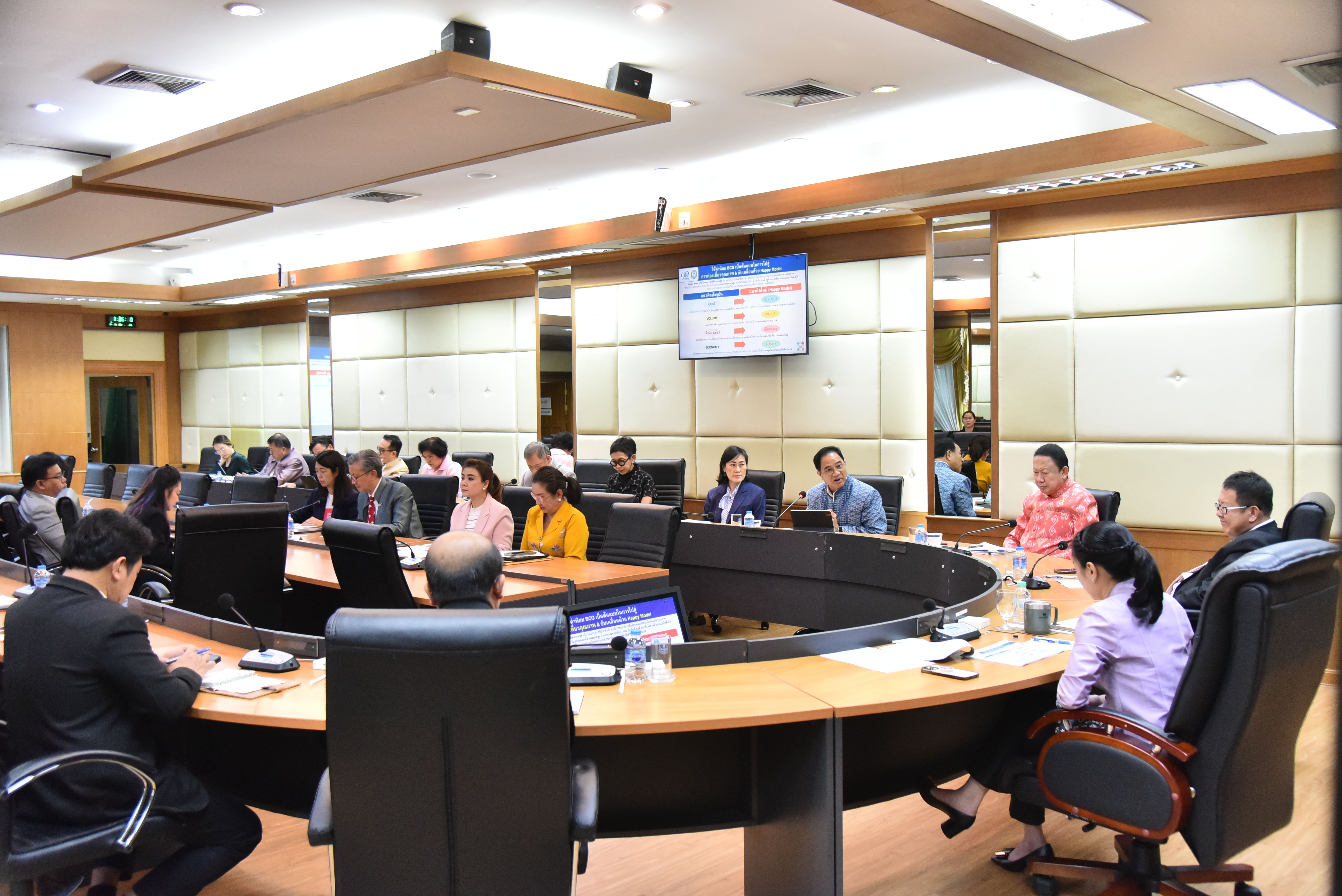 Professionals gather around a curved conference table in a modern meeting room.