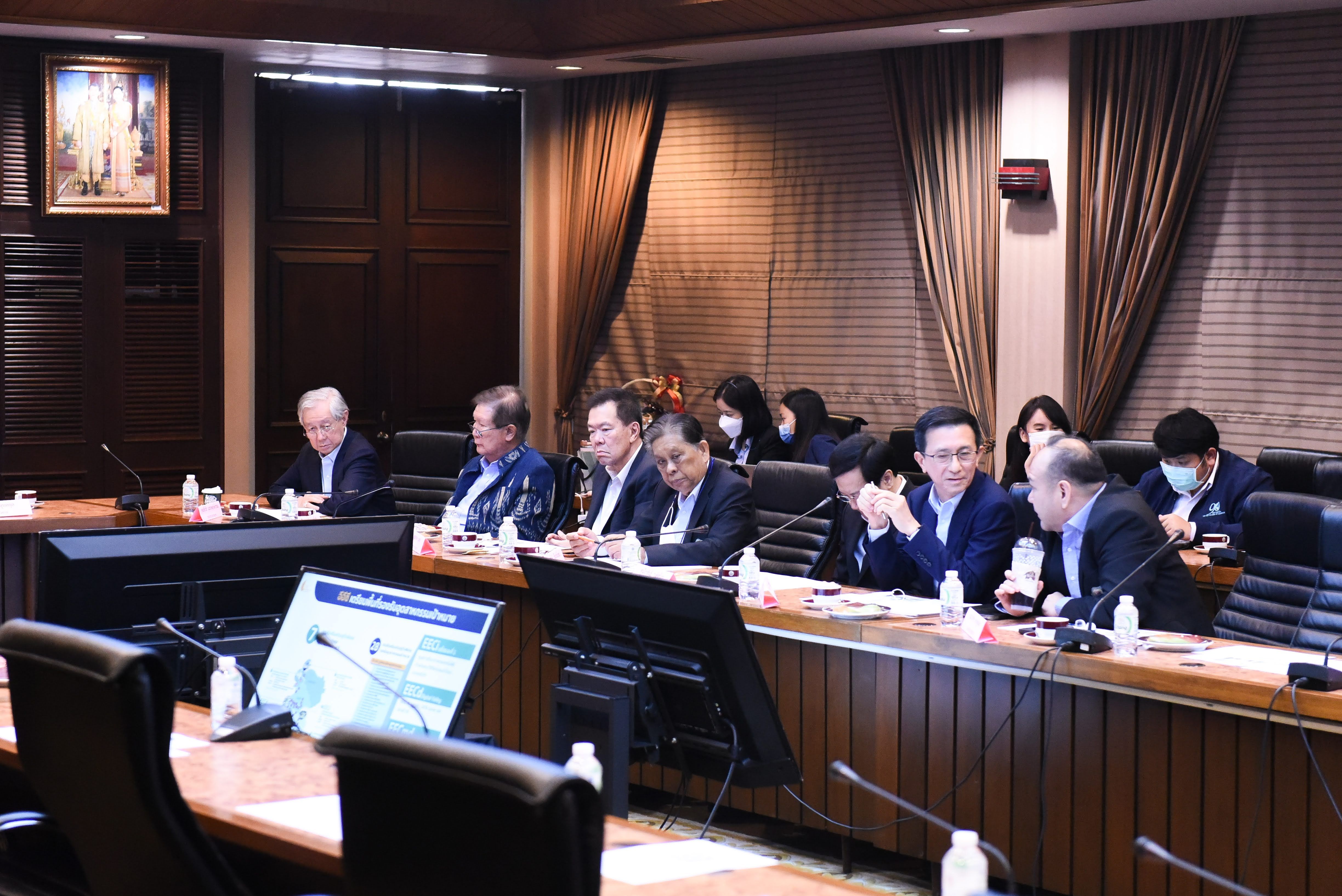 Group of professionals in a formal meeting room discussing matters around a large table.