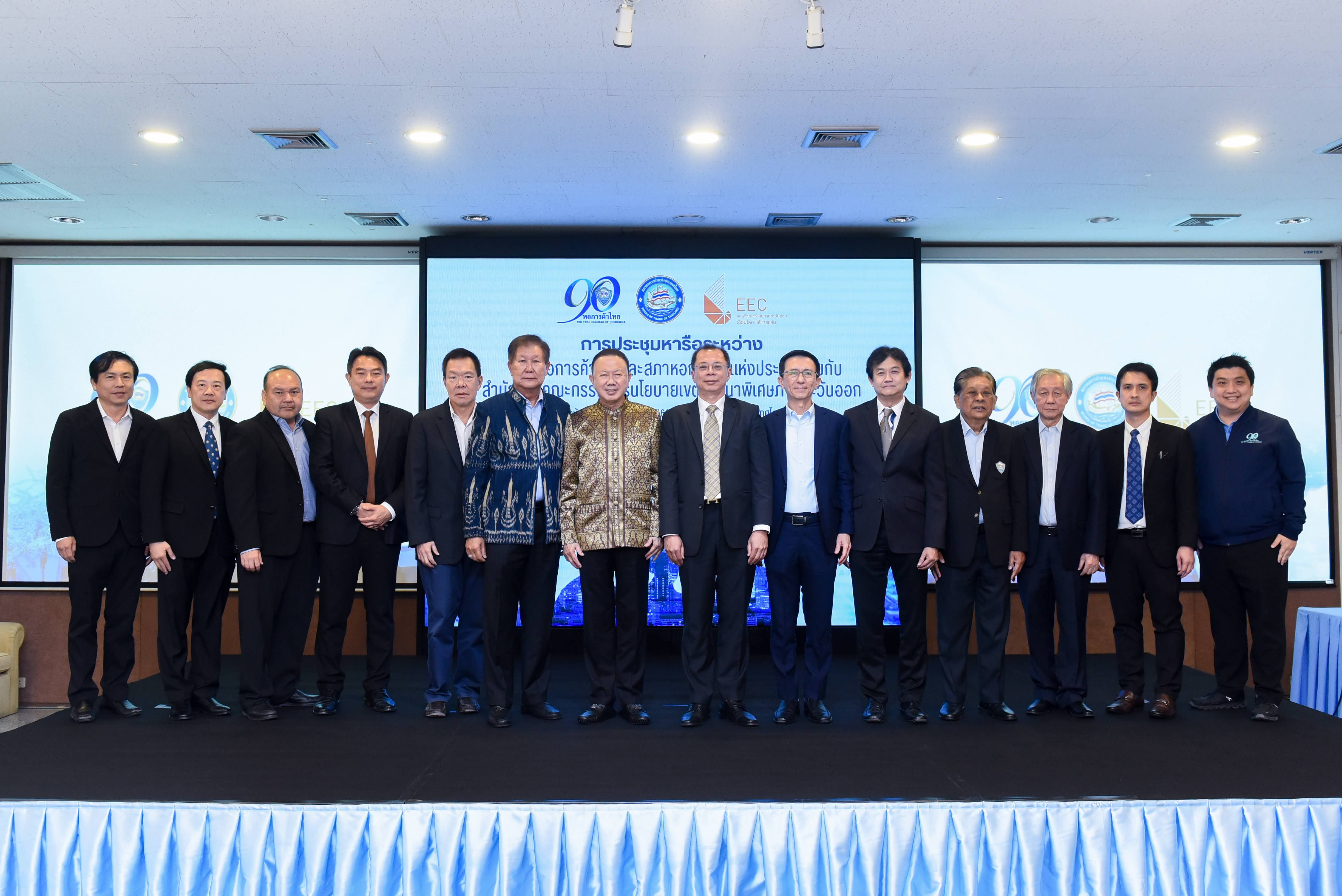 A group of fifteen men in suits standing formally in front of a projection screen.