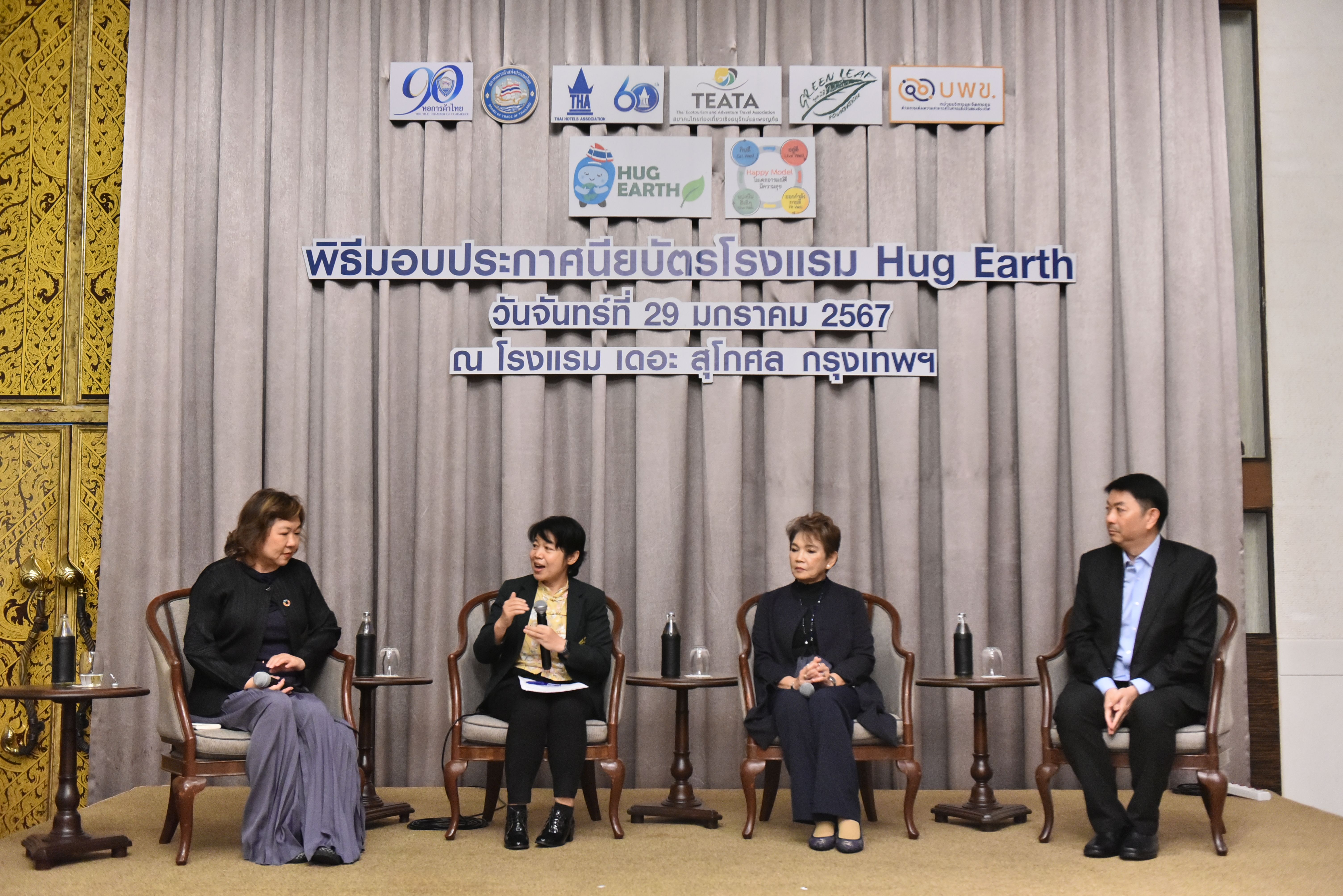 Four panelists, three women and one man, seated on stage in front of a banner.