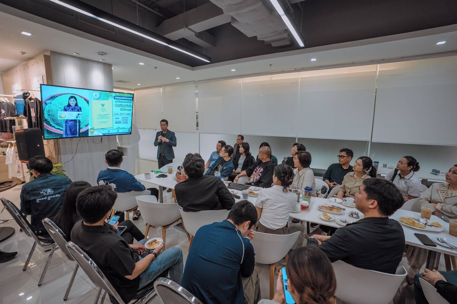 Audience watching a presentation on a large screen in a modern conference room.