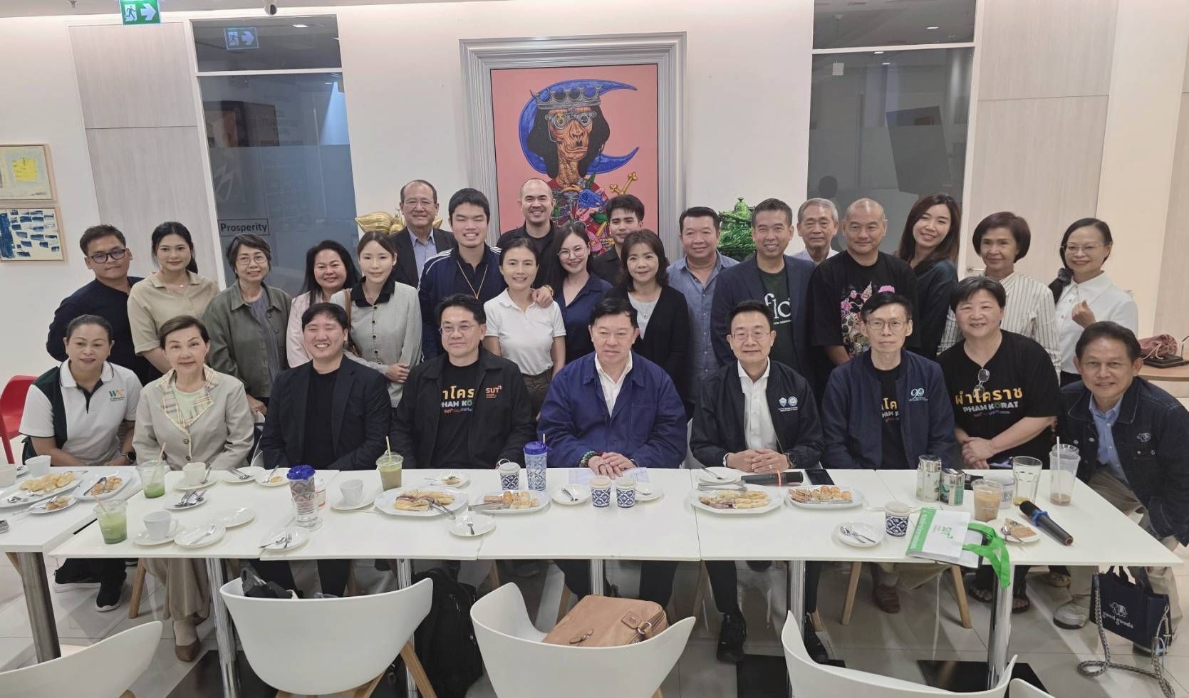 Diverse group of adults gathered around a long table during an indoor social event.