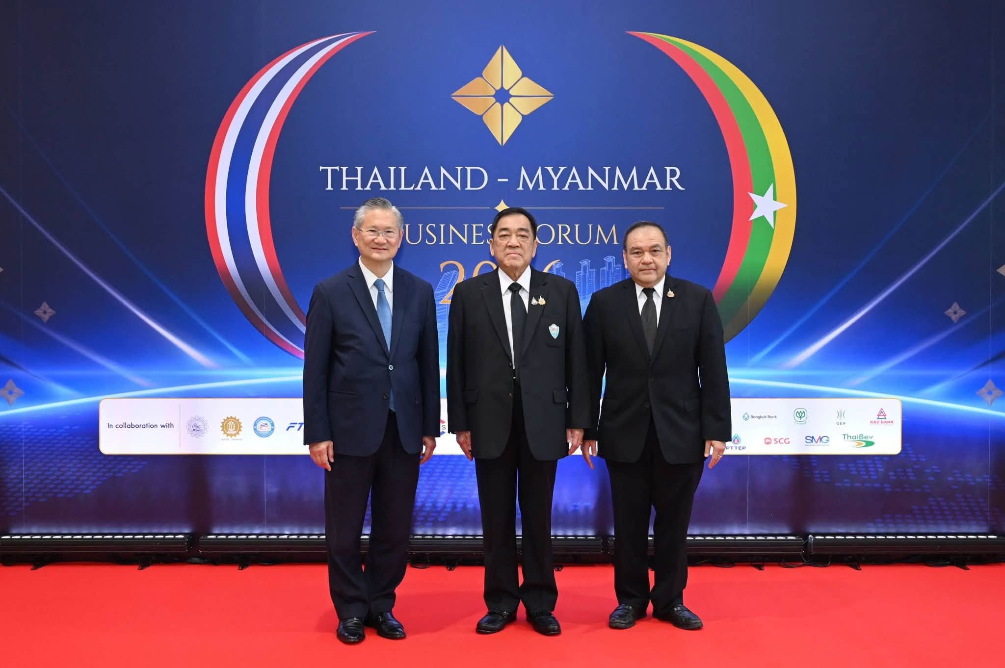 Three men in suits stand before a 'Thailand - Myanmar Business Forum' backdrop.