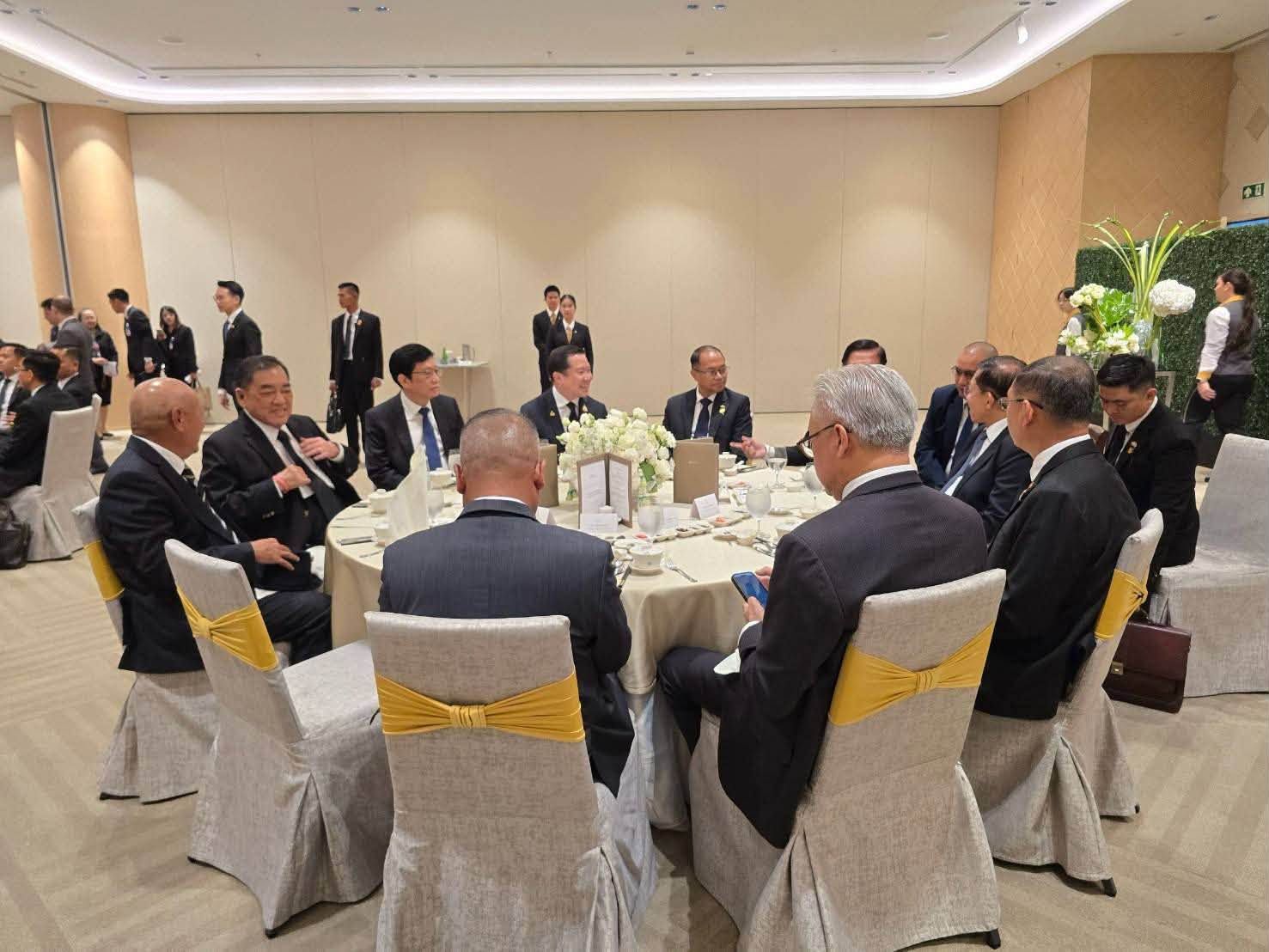 Men in suits seated around a formal round table during a business meeting.