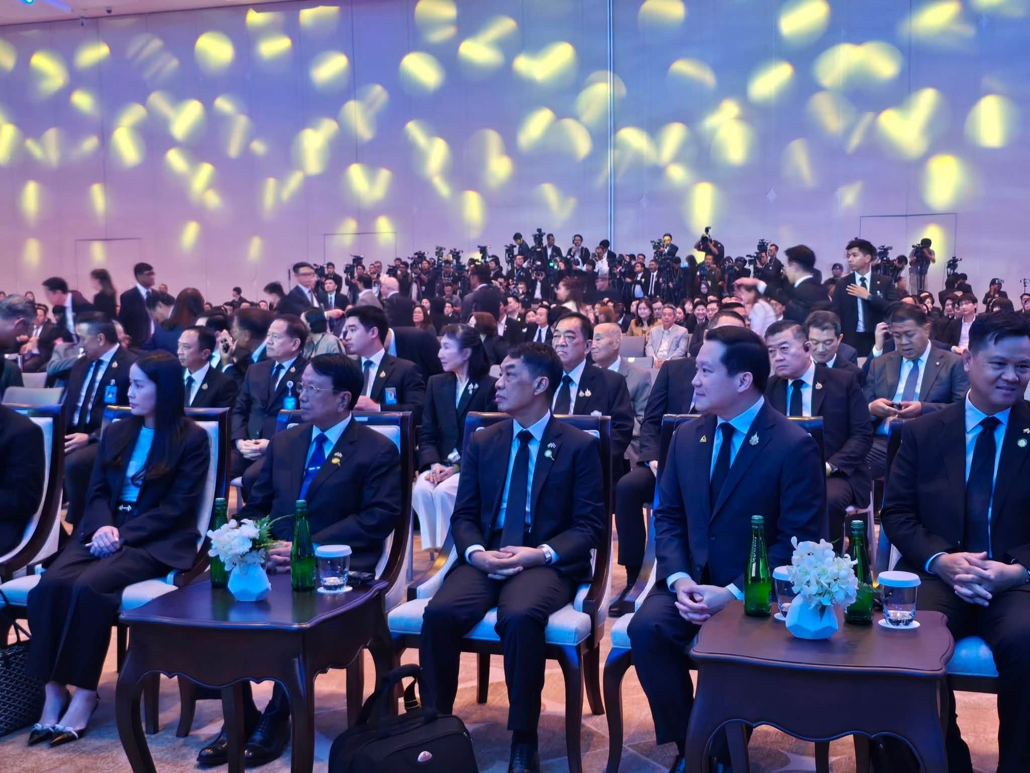 A large audience of professionals seated in a dimly lit conference hall for an event.