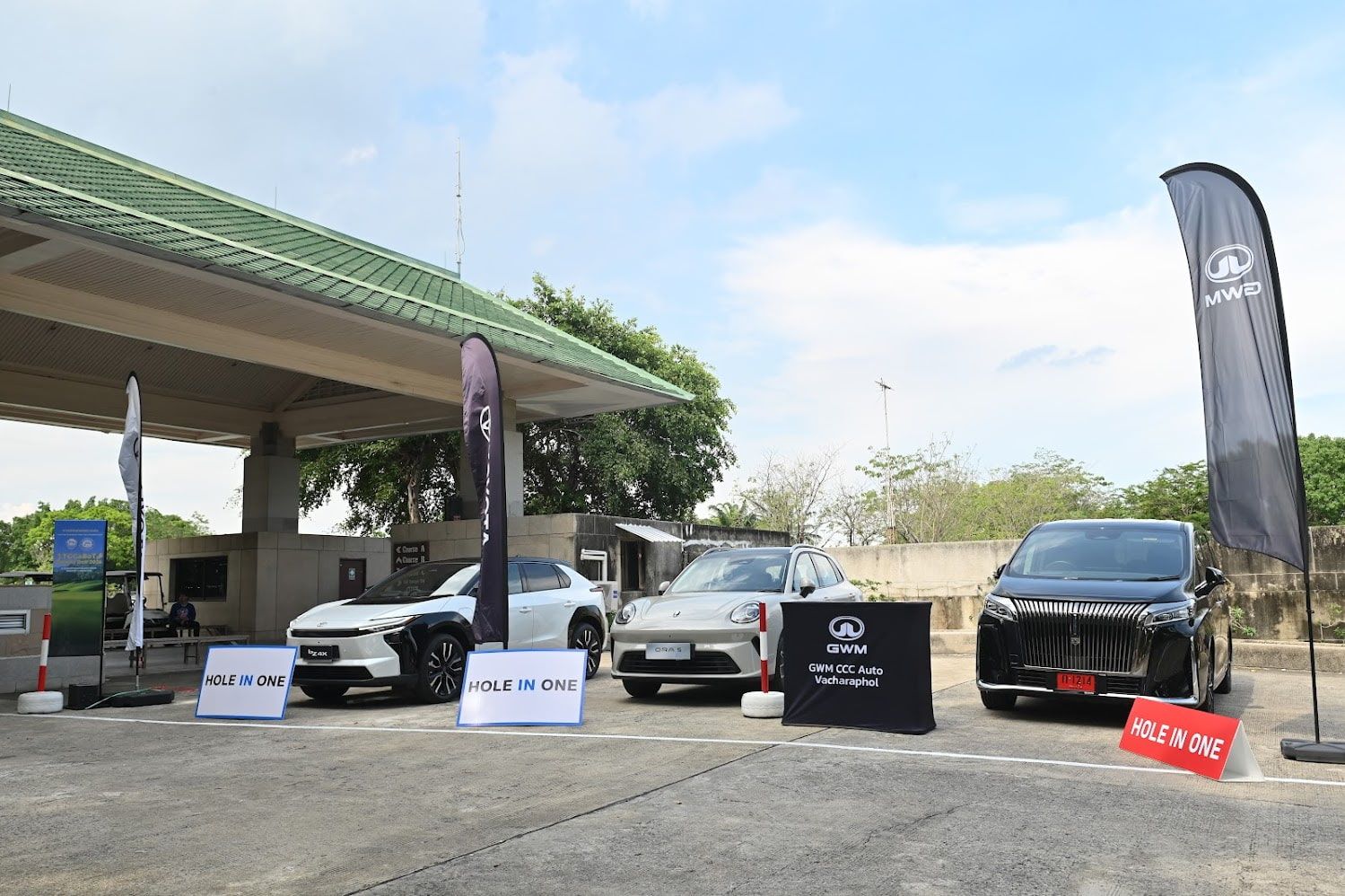 Three modern electric vehicles displayed under a station canopy with promotional banners and signage.