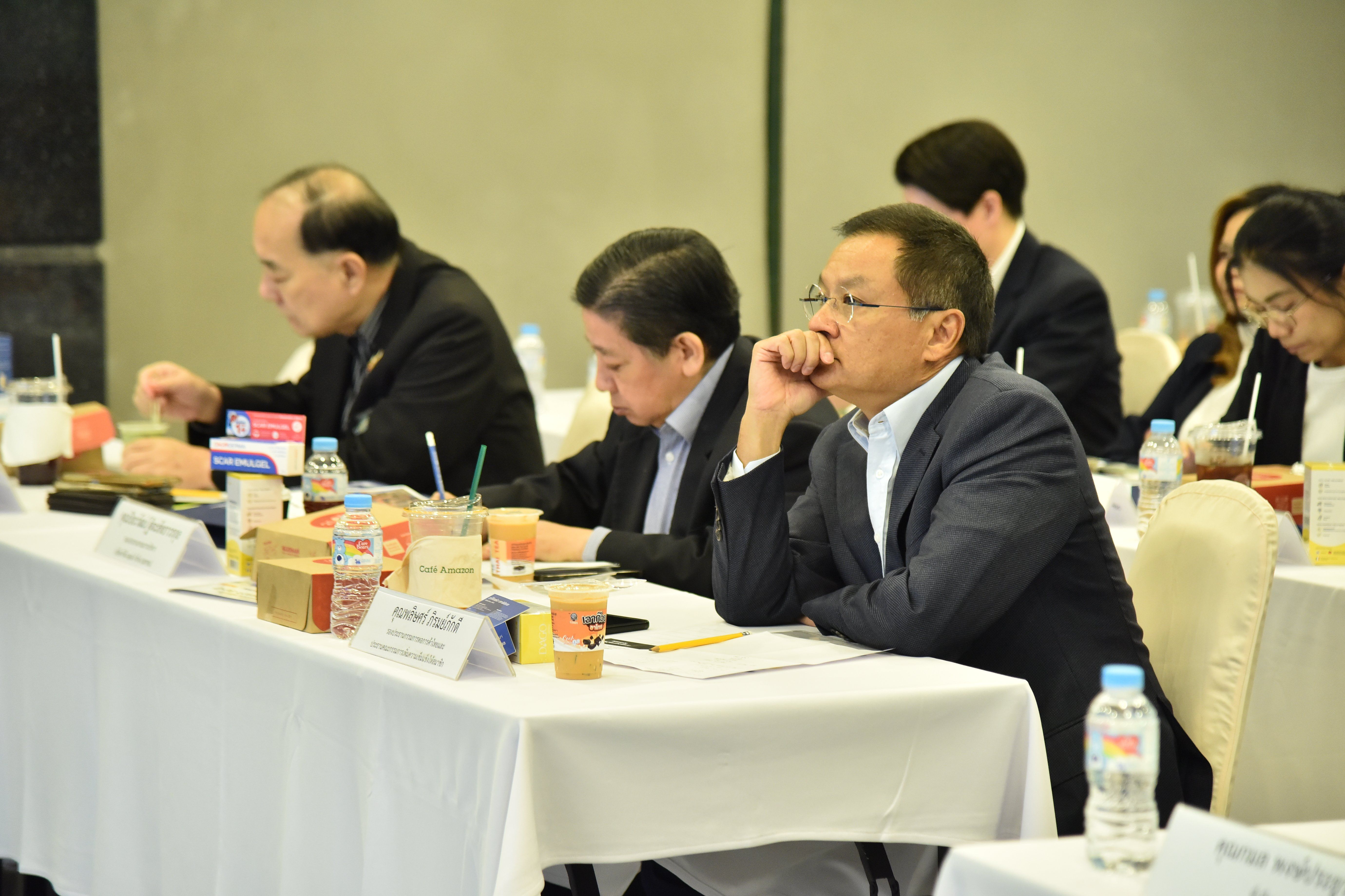 Man in dark suit and glasses listens attentively at a professional conference table.